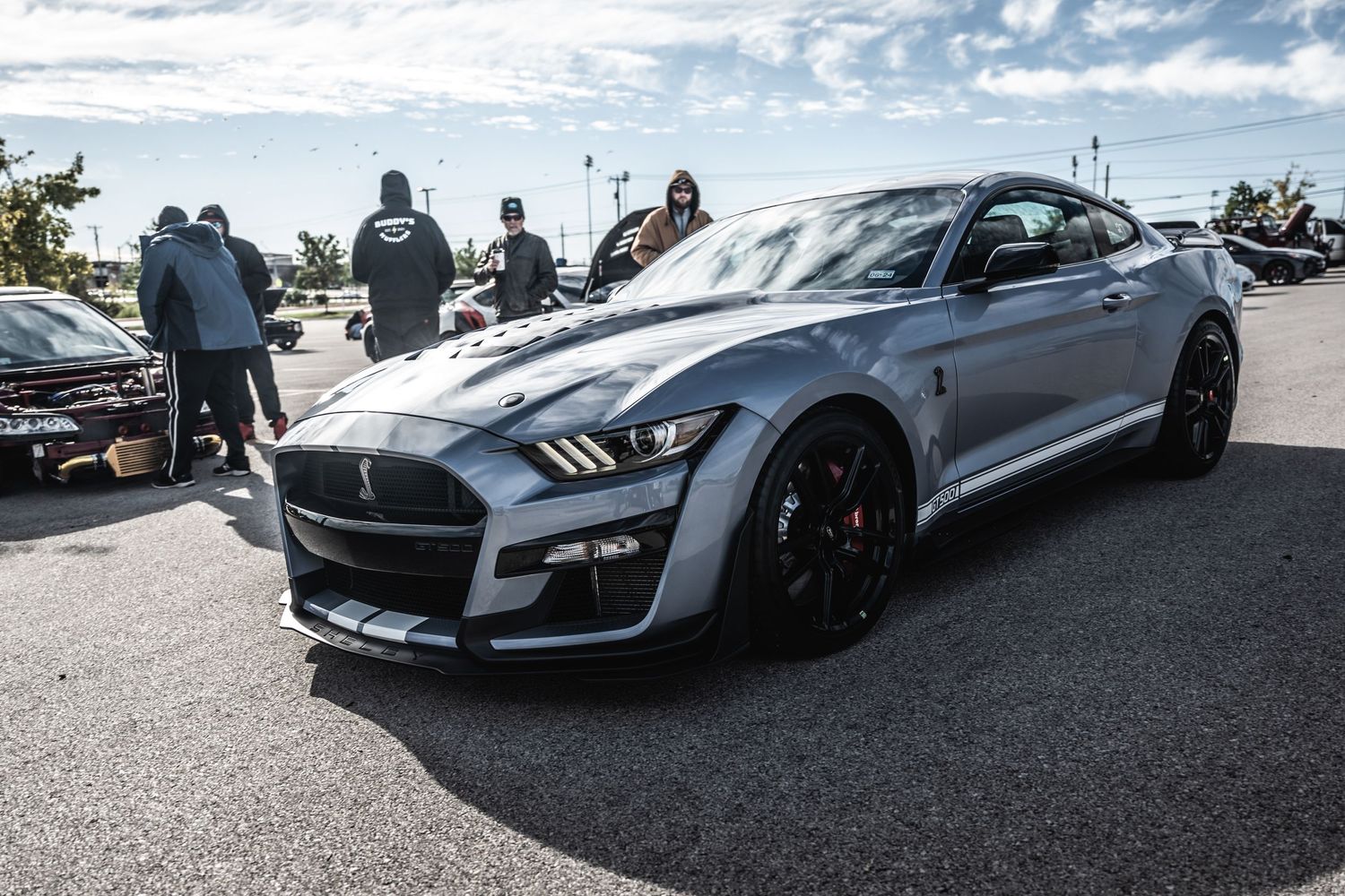 Silver Ford Mustang Shelby GT500 with black racing stripes parked at automotive event.