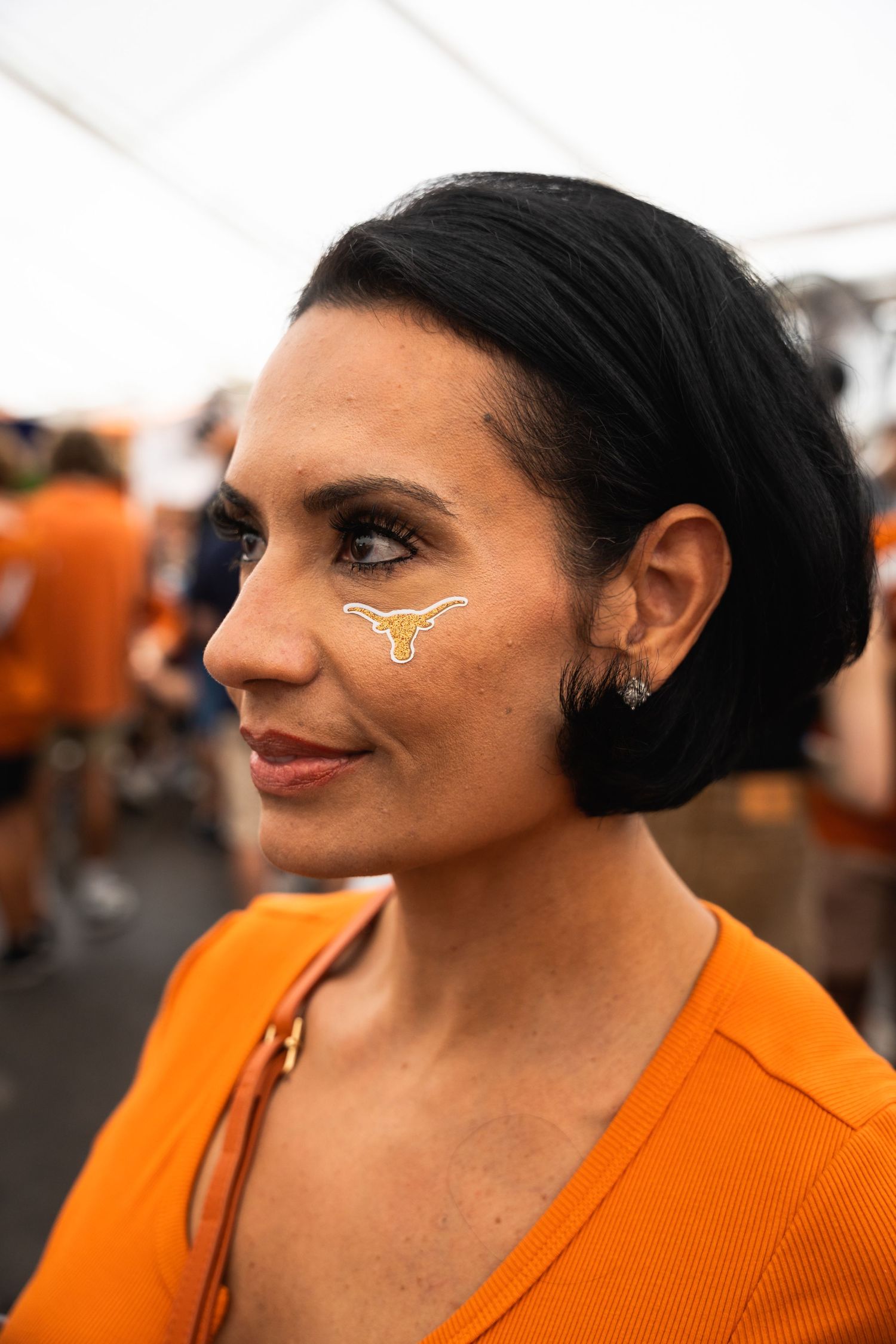 Person wearing orange with Texas Longhorns face paint at a sporting event.