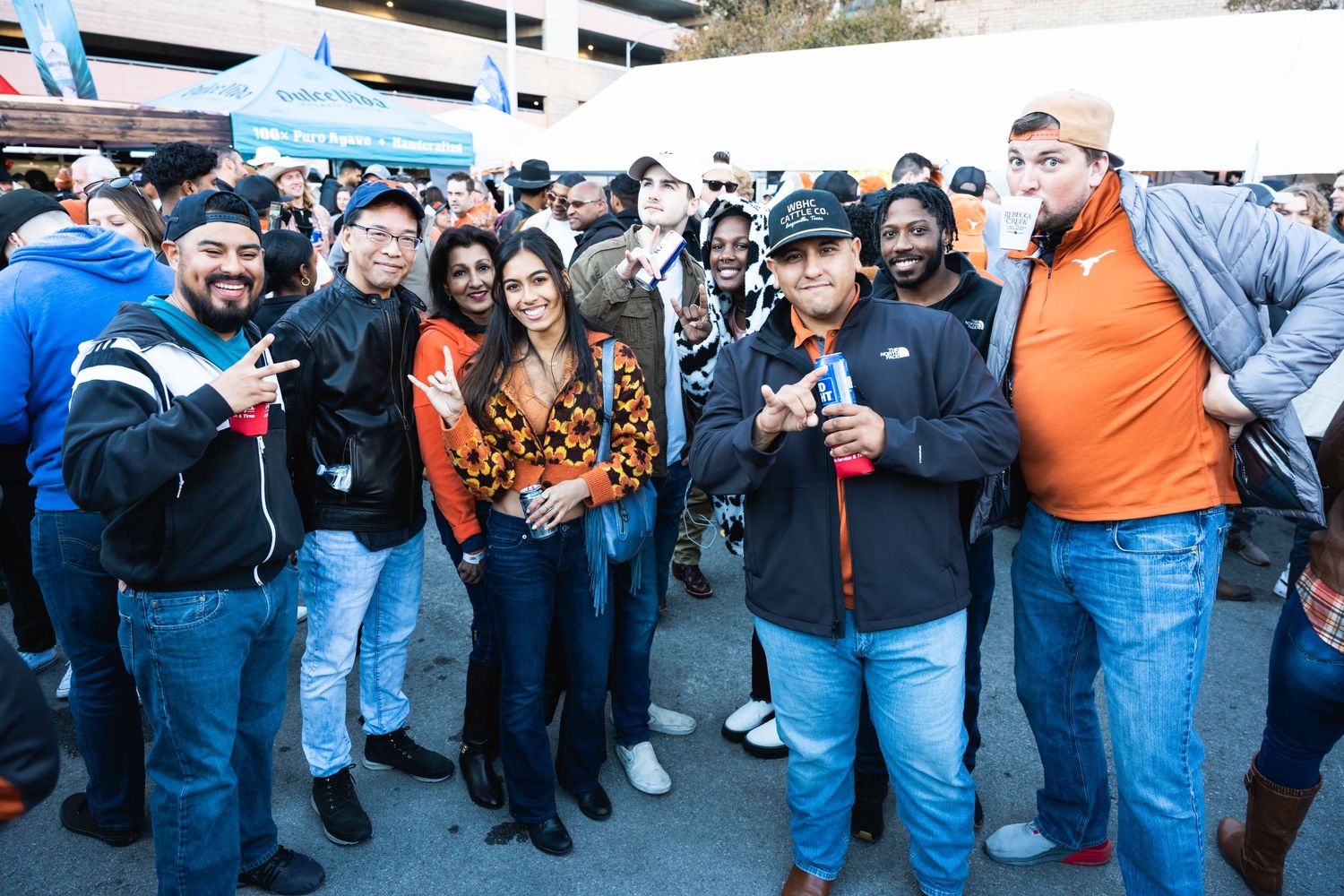 Large group of sports fans socializing at an outdoor tailgate party.