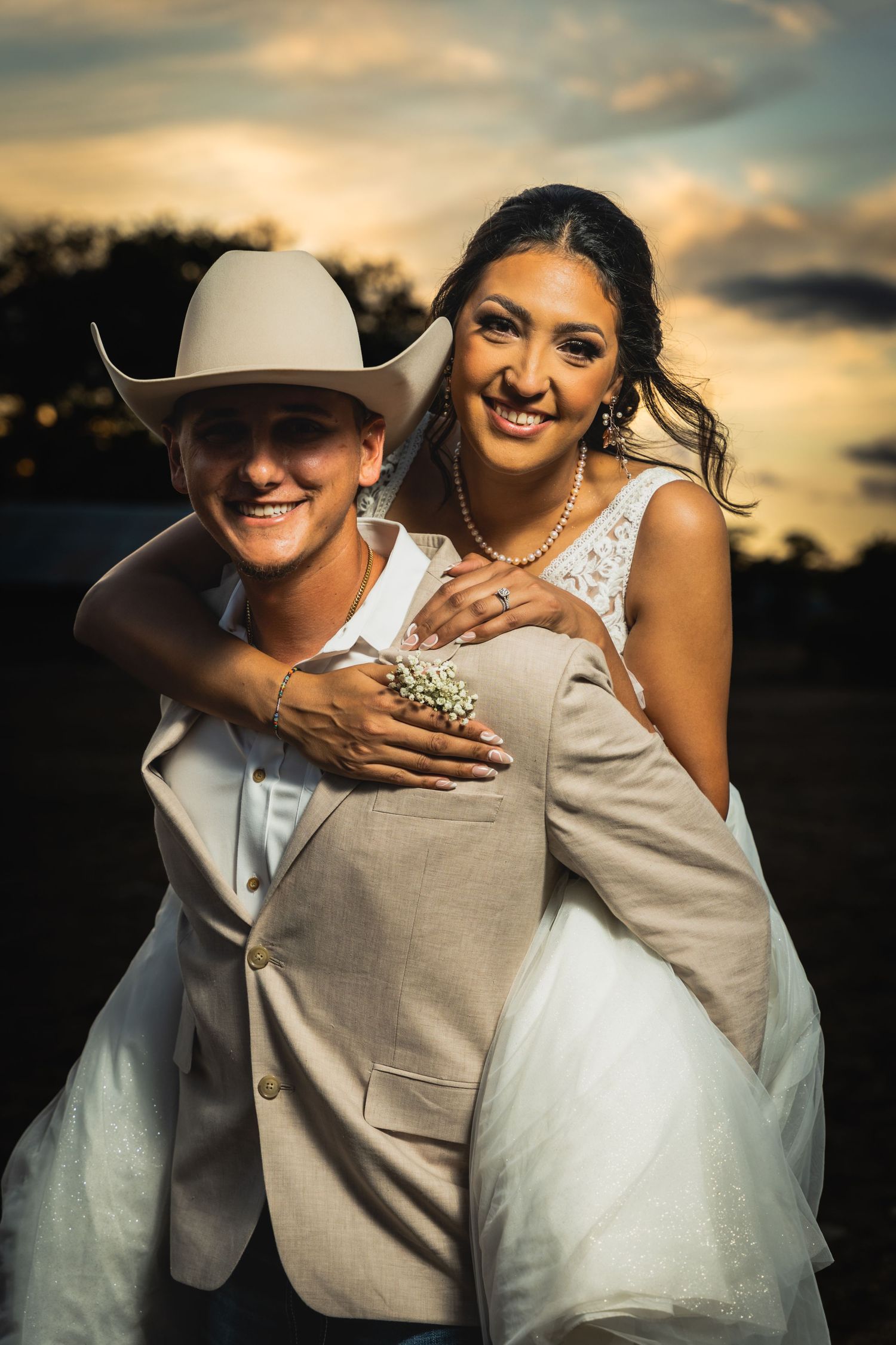 Playful piggyback wedding portrait at sunset in western attire.