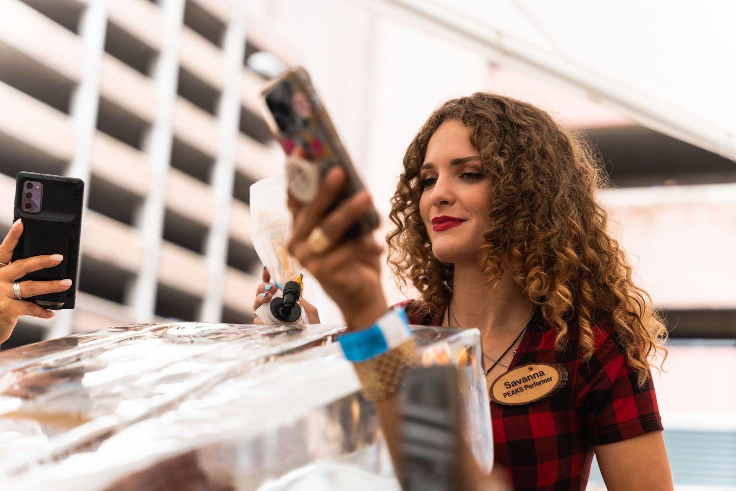 Staff member in plaid shirt pouring drinks at an outdoor beverage station.