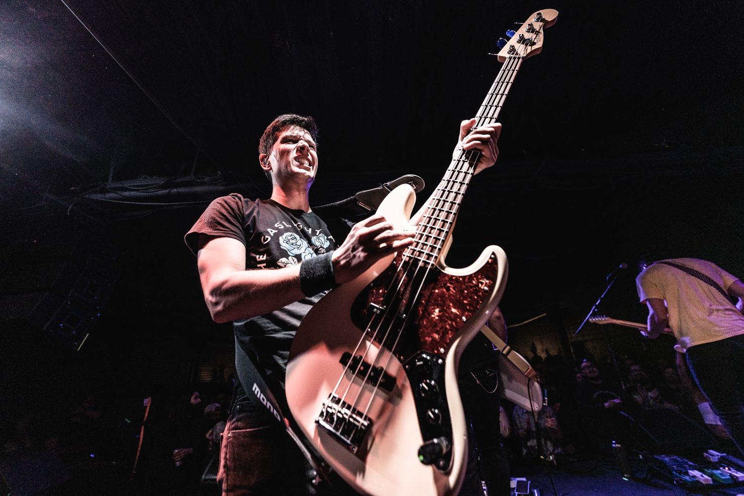 Bassist plays low-angled shot of instrument during energetic stage performance.