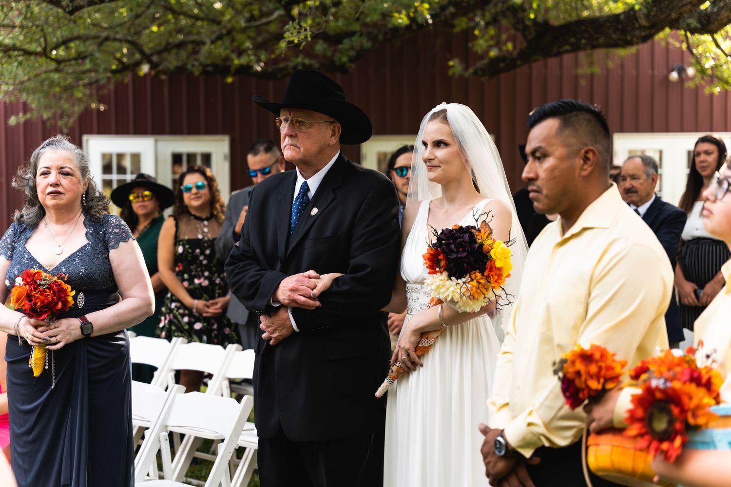 A wedding ceremony in progress with attendants and guests gathered outdoors.