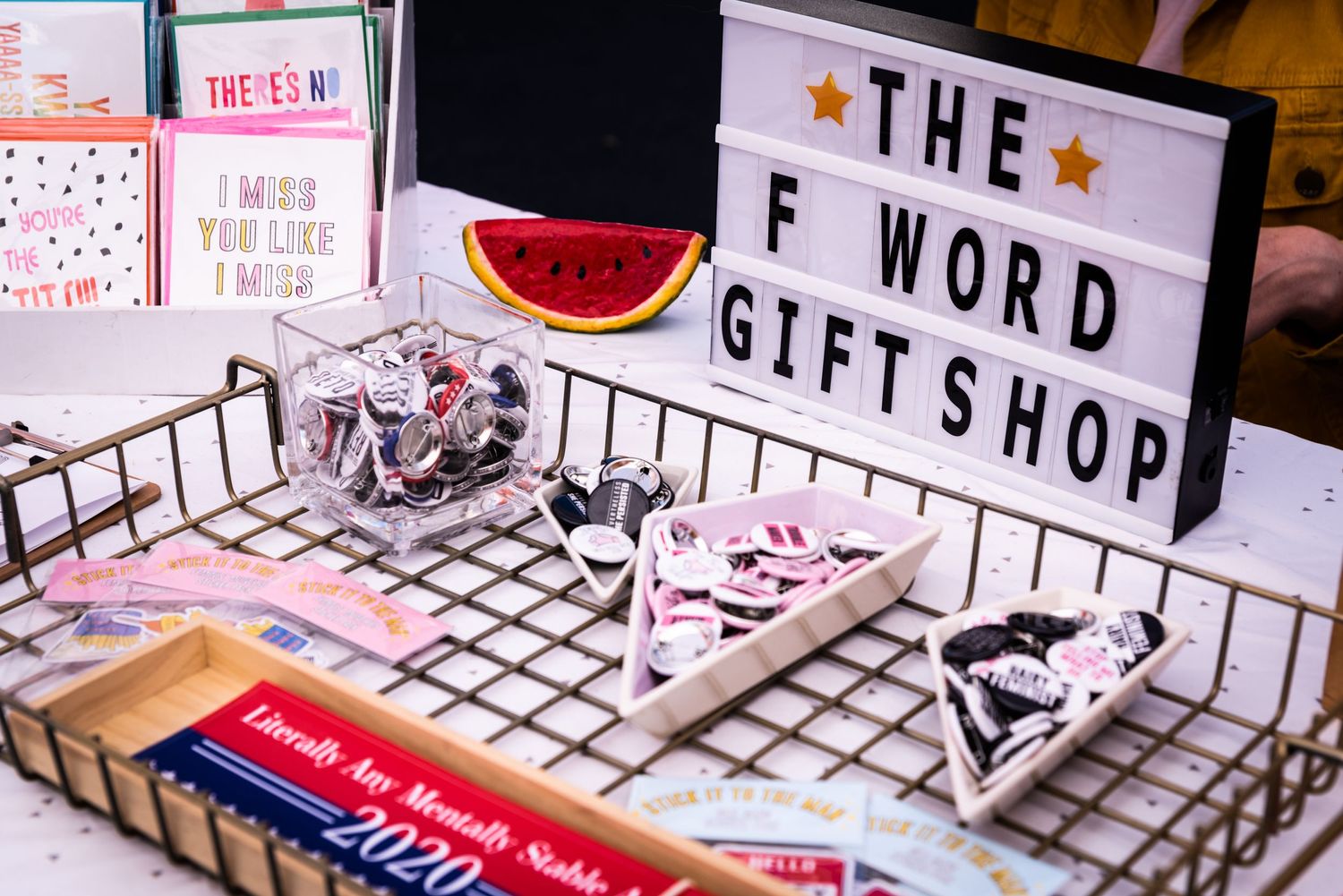 Retail display with lightbox sign reading 'The Word Giftshop' and merchandise in wire basket.