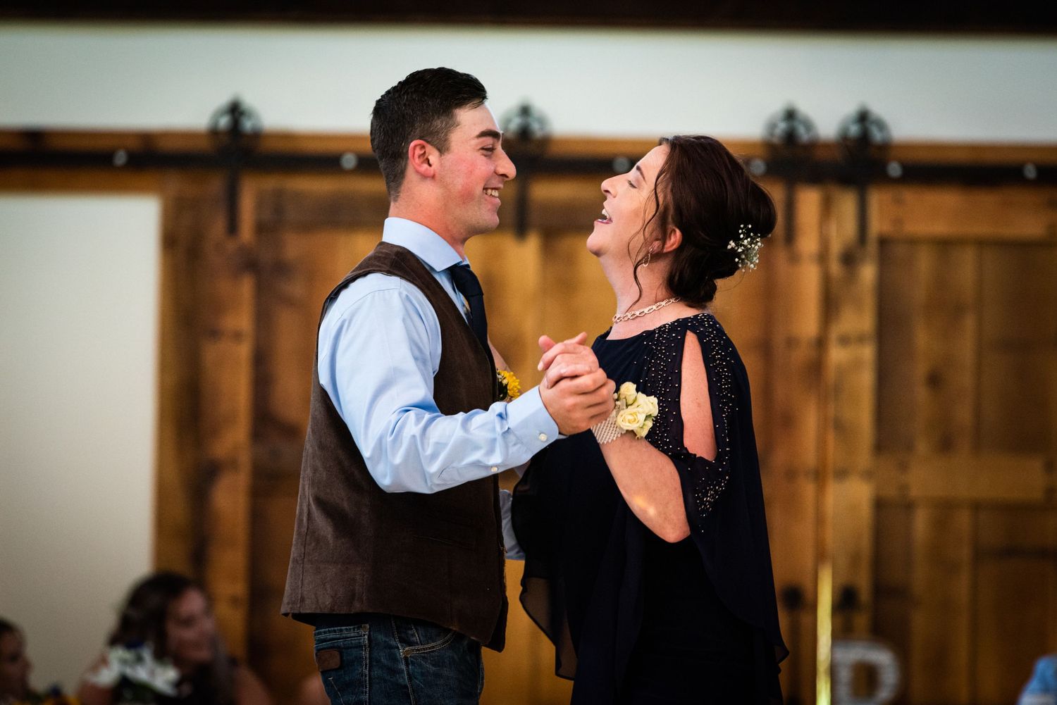 Couple shares joyful moment while dancing at rustic barn wedding reception.