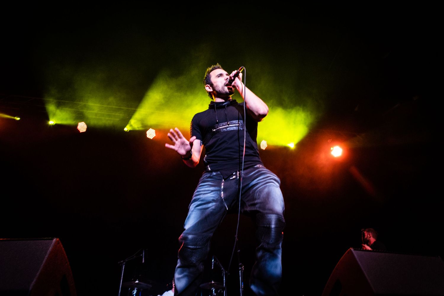 Lead singer performs energetically against vibrant green stage lighting during concert.