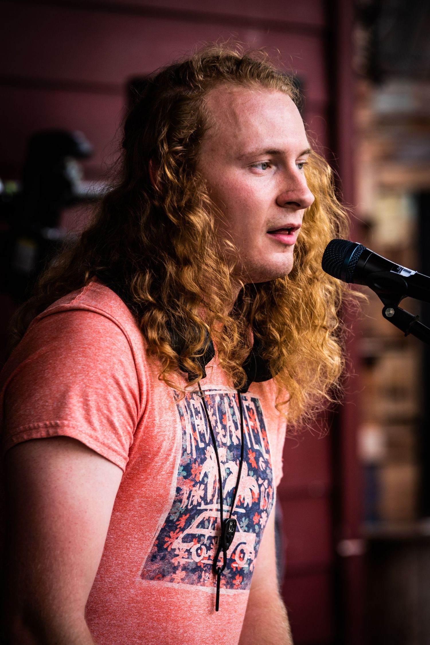 Musician with long curly hair performs on keyboard while singing at an outdoor venue in Austin.