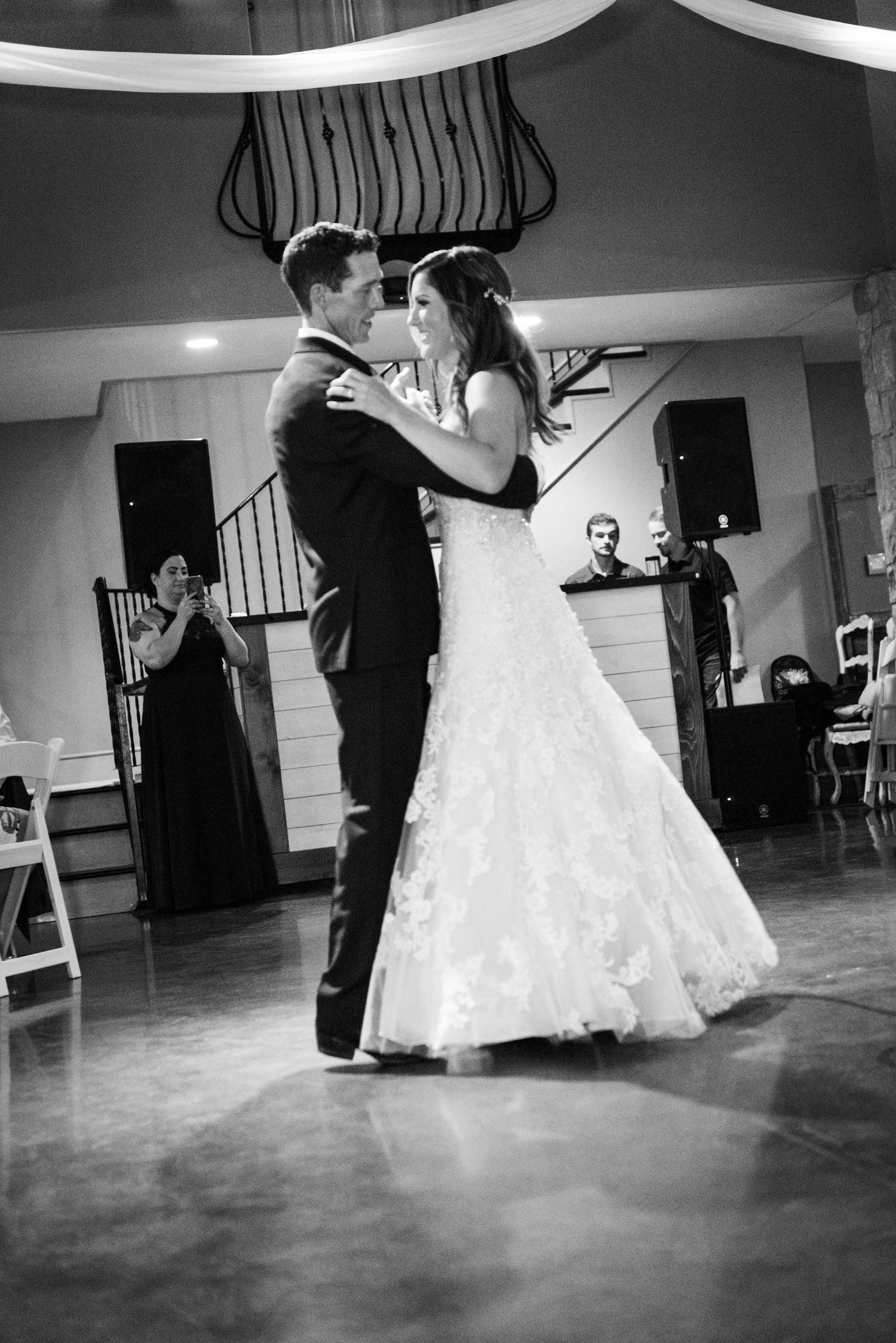 A romantic first dance moment captured in black and white under decorative venue draping.