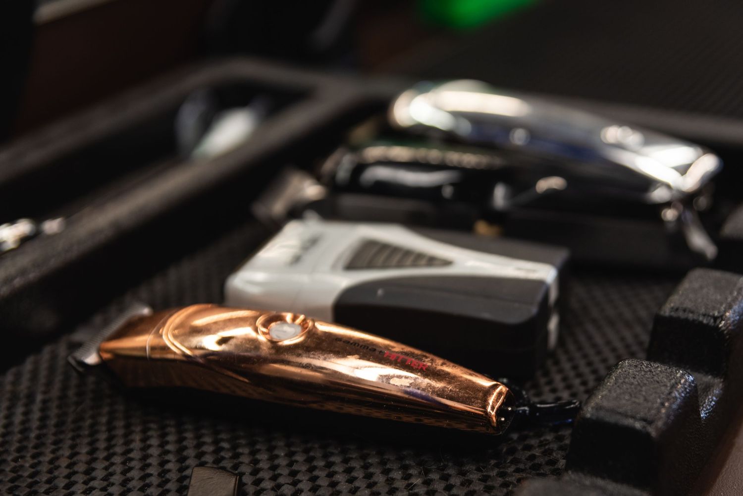 Professional barber tools and clippers arranged on textured black surface.