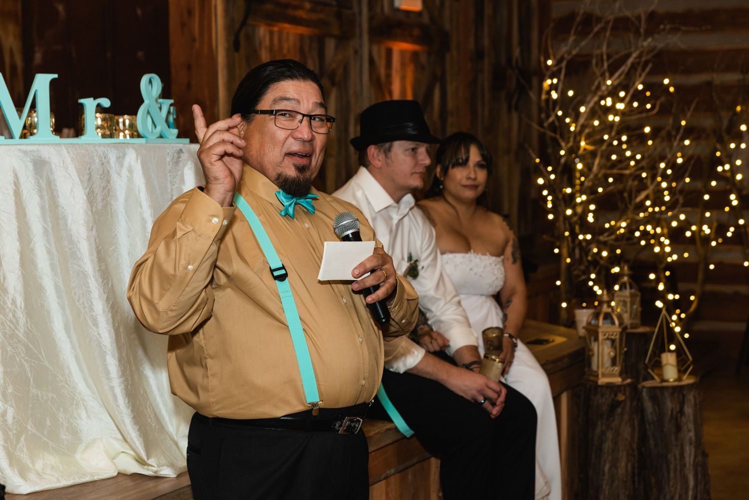 Wedding reception guests enjoy festivities in a rustic barn venue with twinkle lights.