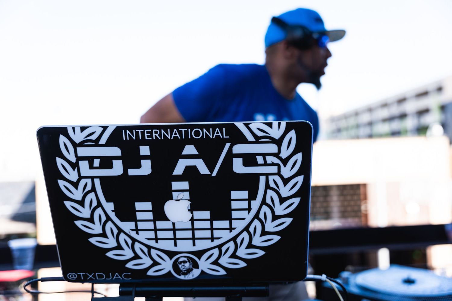 DJ performs at an outdoor event with equipment displaying an International DJ A/S logo.