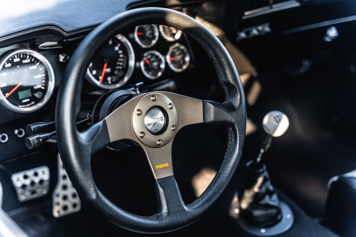 Sports car dashboard with performance gauges and racing steering wheel.
