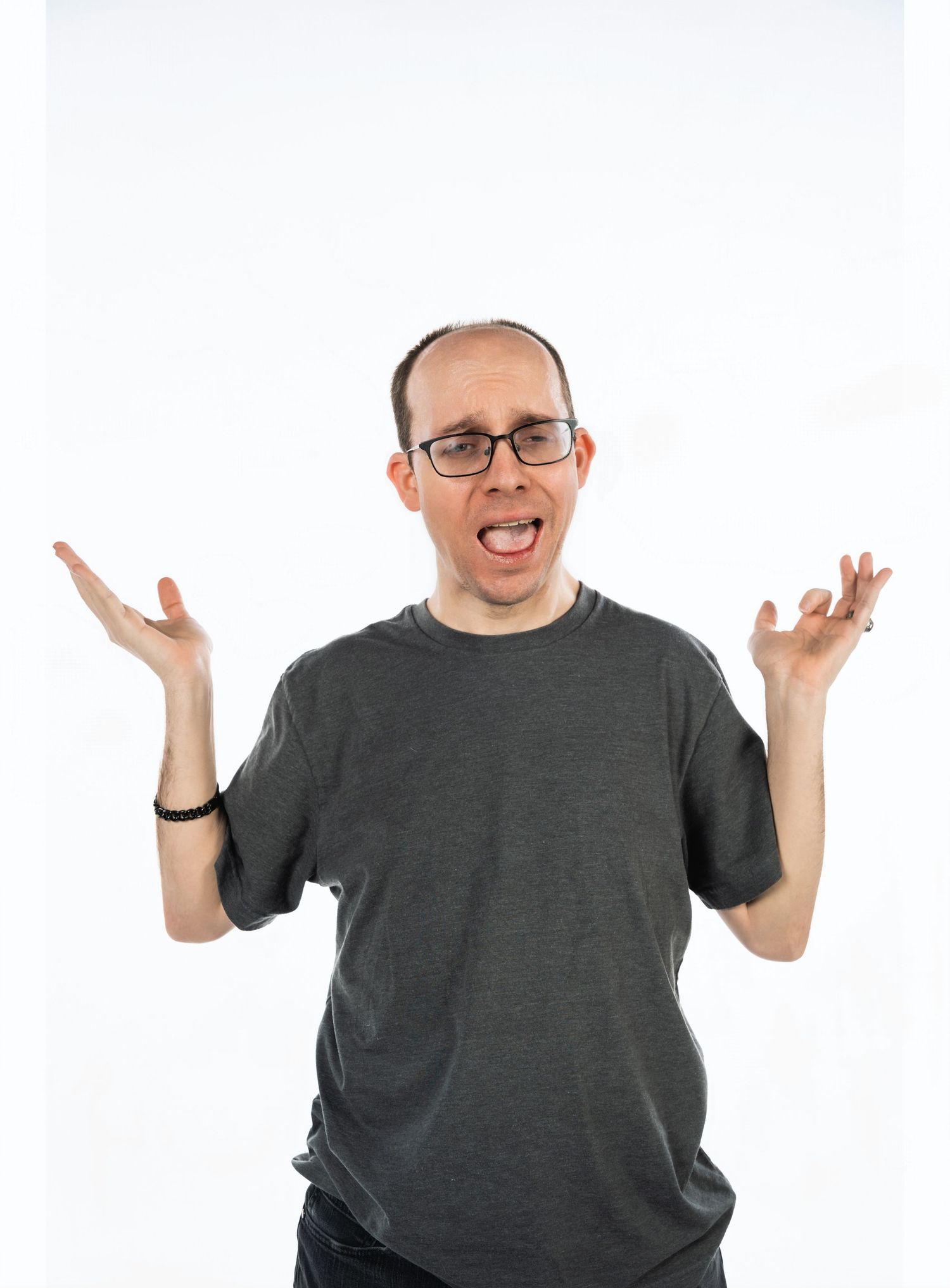 A person in grey shirt gestures expressively with raised hands against white background.