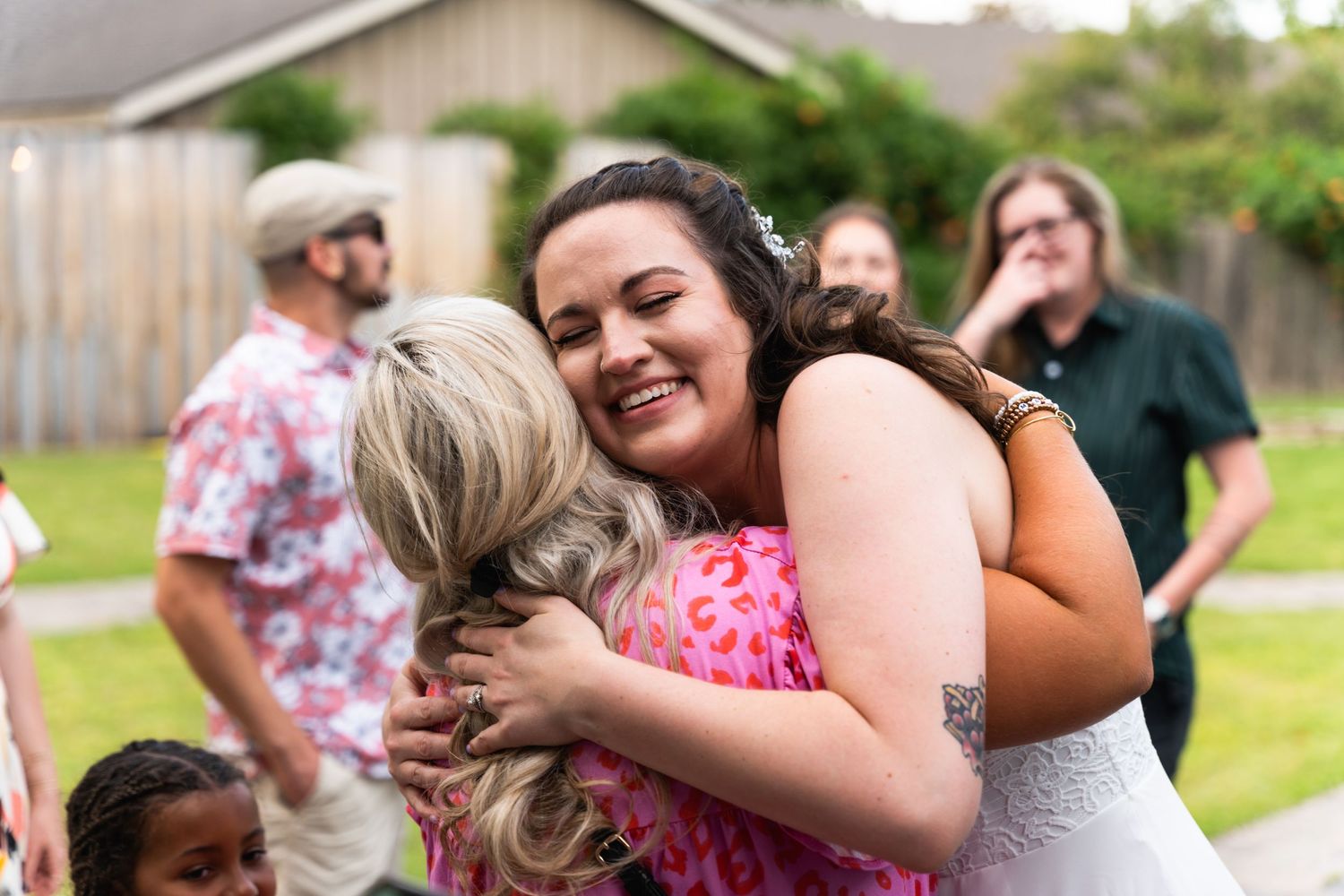Candid moment of joyful embrace at outdoor gathering with people wearing colorful summer attire.
