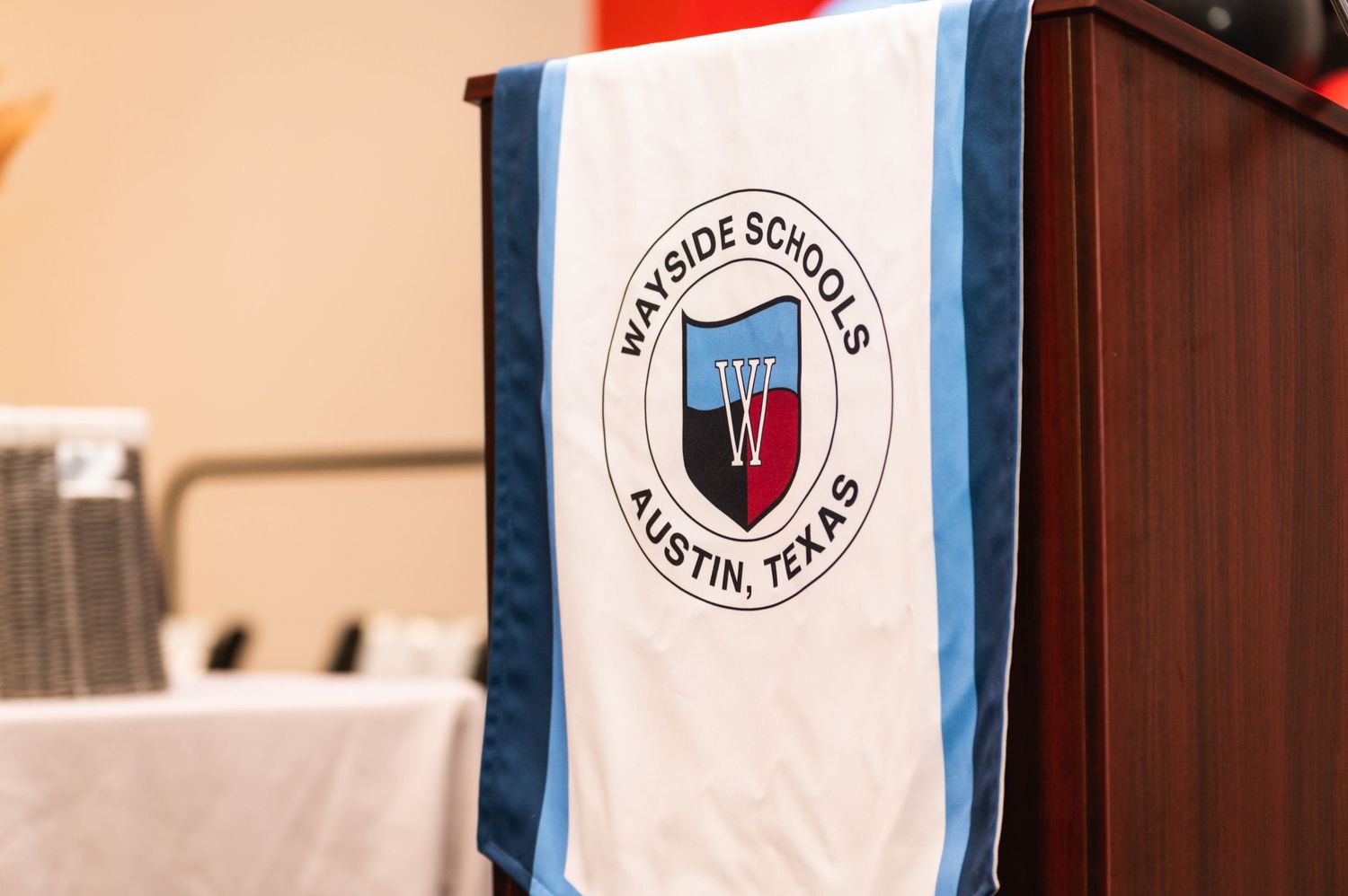 Academy of Thought banner with school logo displayed on podium during graduation ceremony.