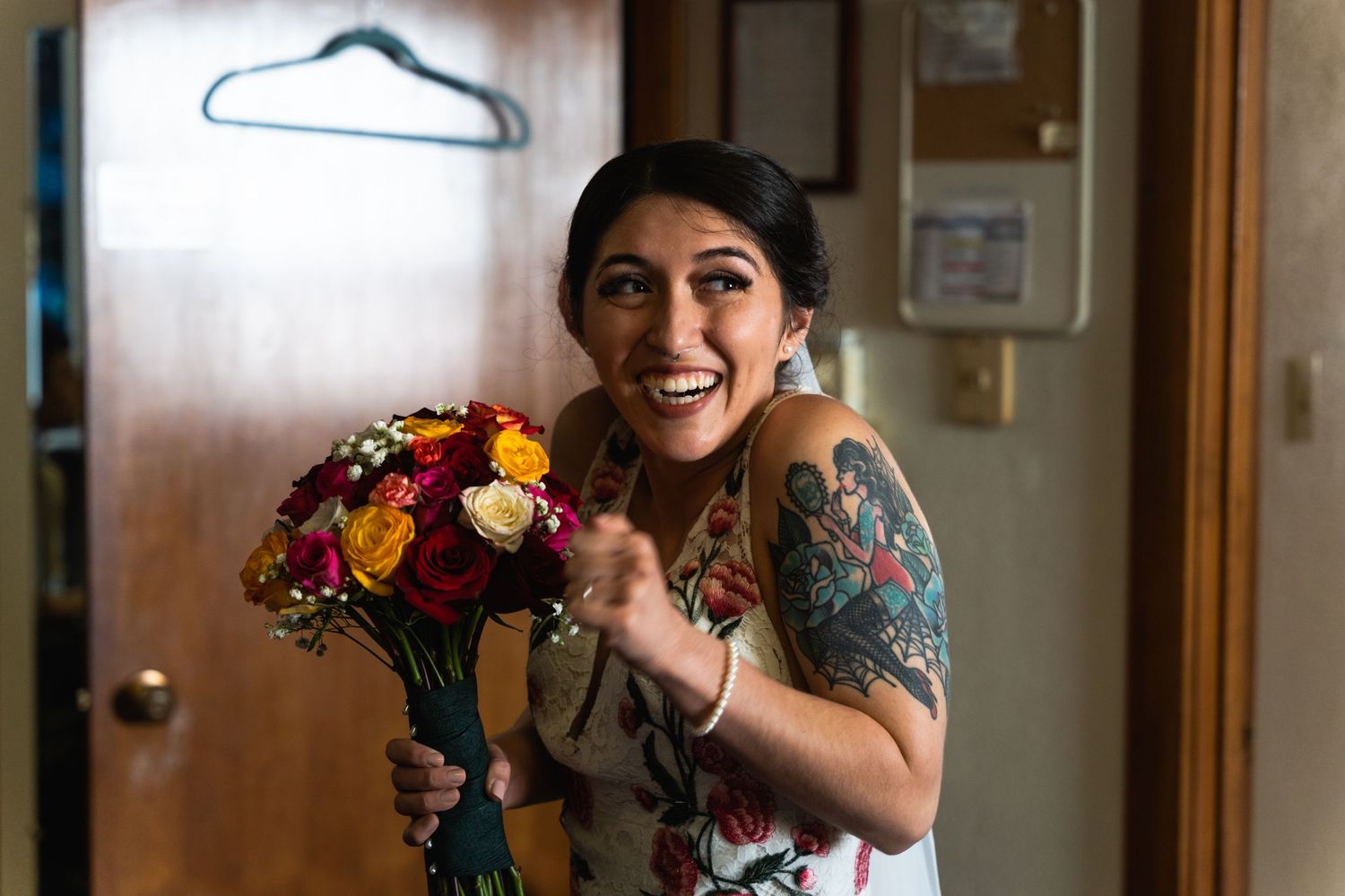 Someone holds a vibrant bouquet of orange and purple flowers while showing off their tattoo sleeve.
