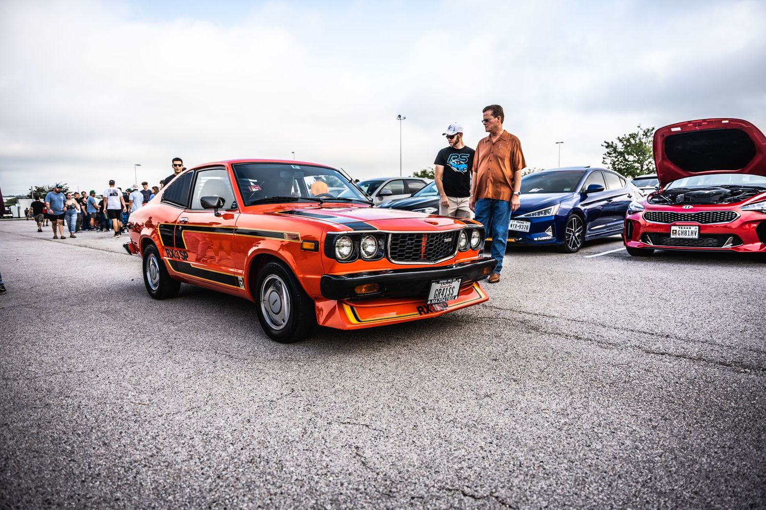 Classic orange BMW at a car show with spectators in background.