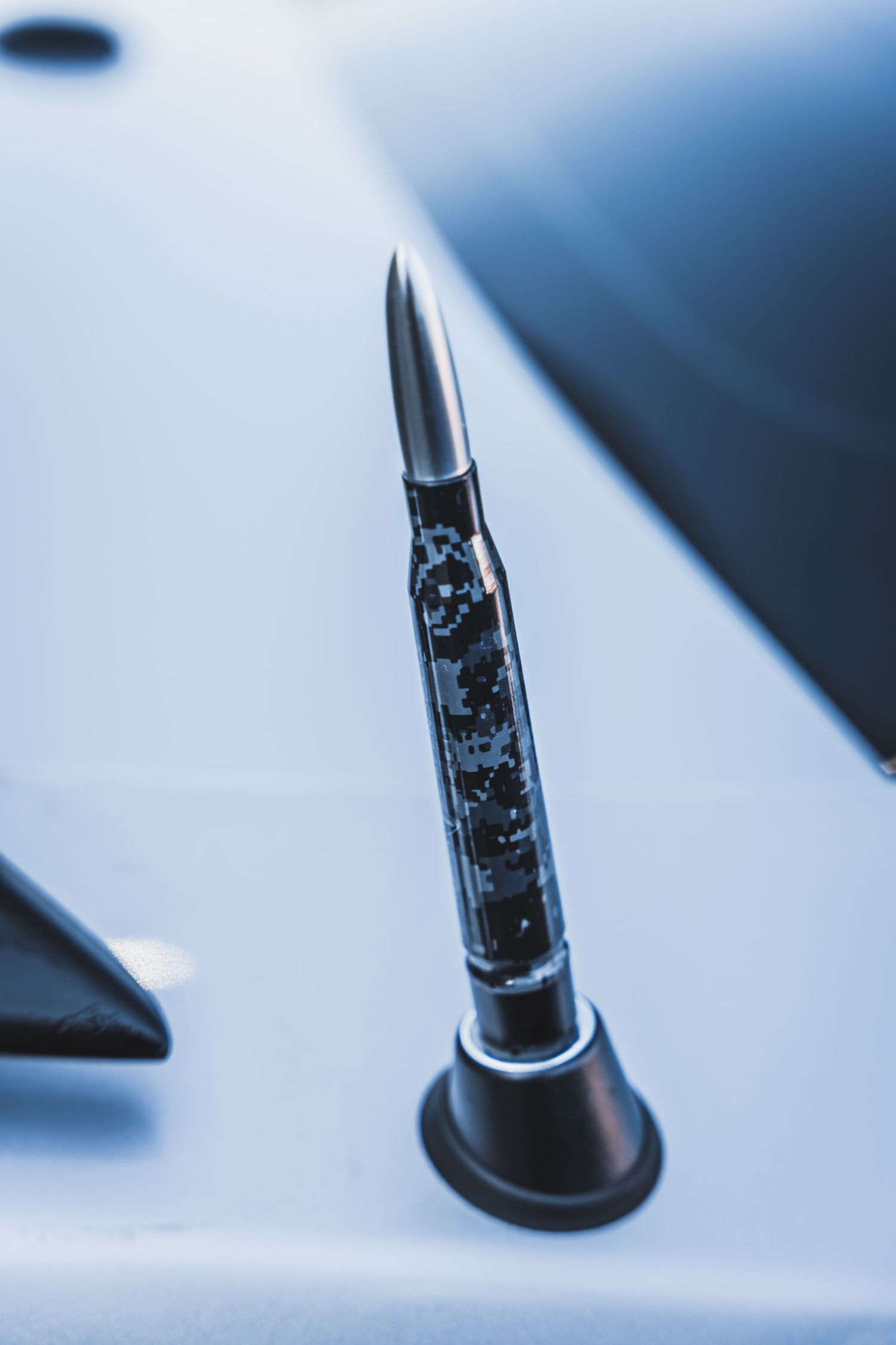 Macro shot of a decorative black car antenna against blurred background.