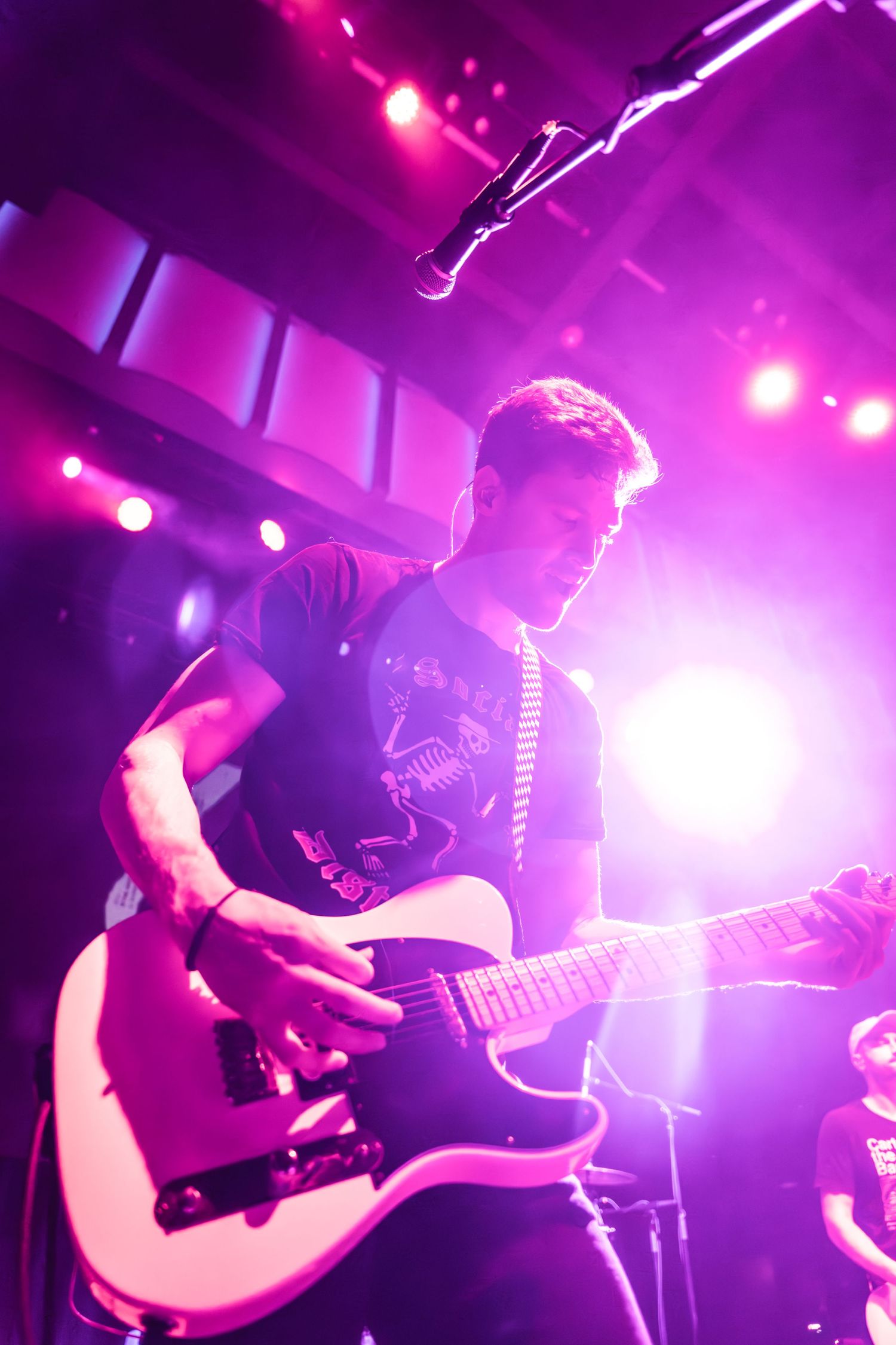 Guitarist silhouetted against purple stage lights during energetic performance.