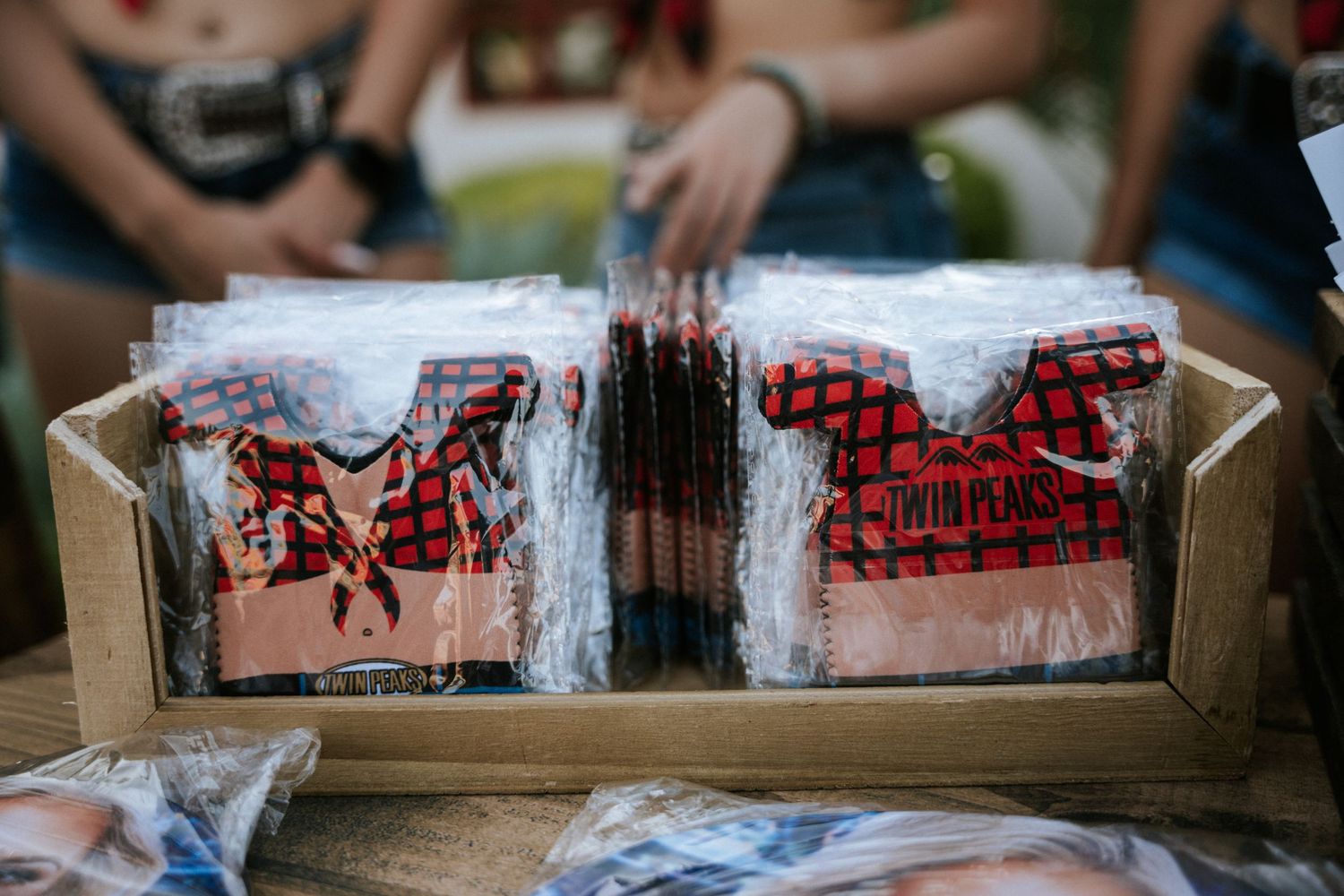 Red patterned merchandise displayed in clear plastic packaging arranged in a wooden box.