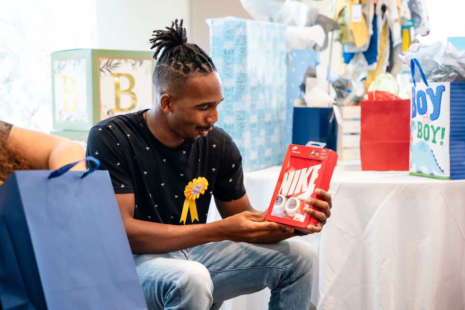 A guest at a baby shower examines a red gift bag during the celebration.