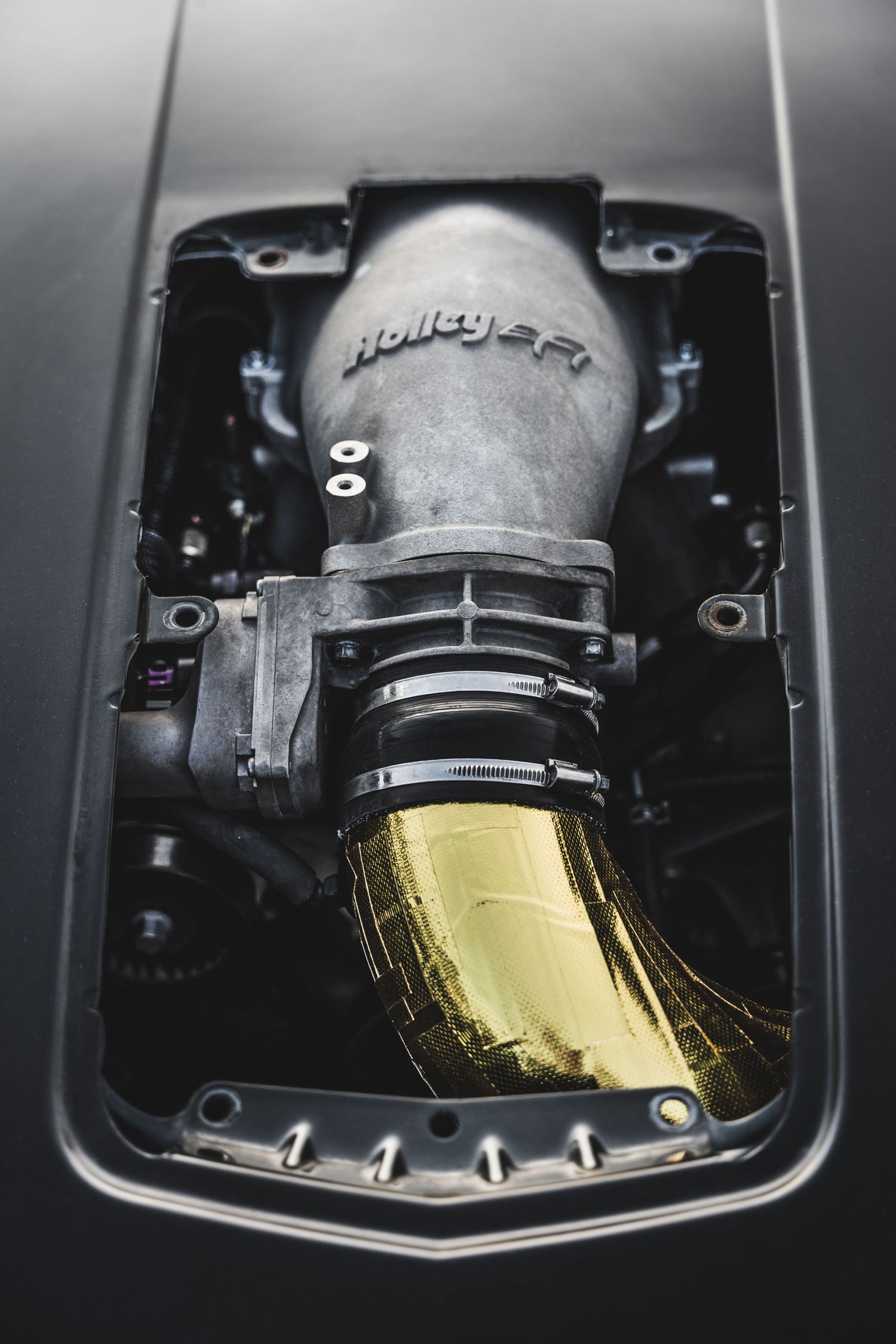 Close-up detail of a gold-tipped performance car intake system.