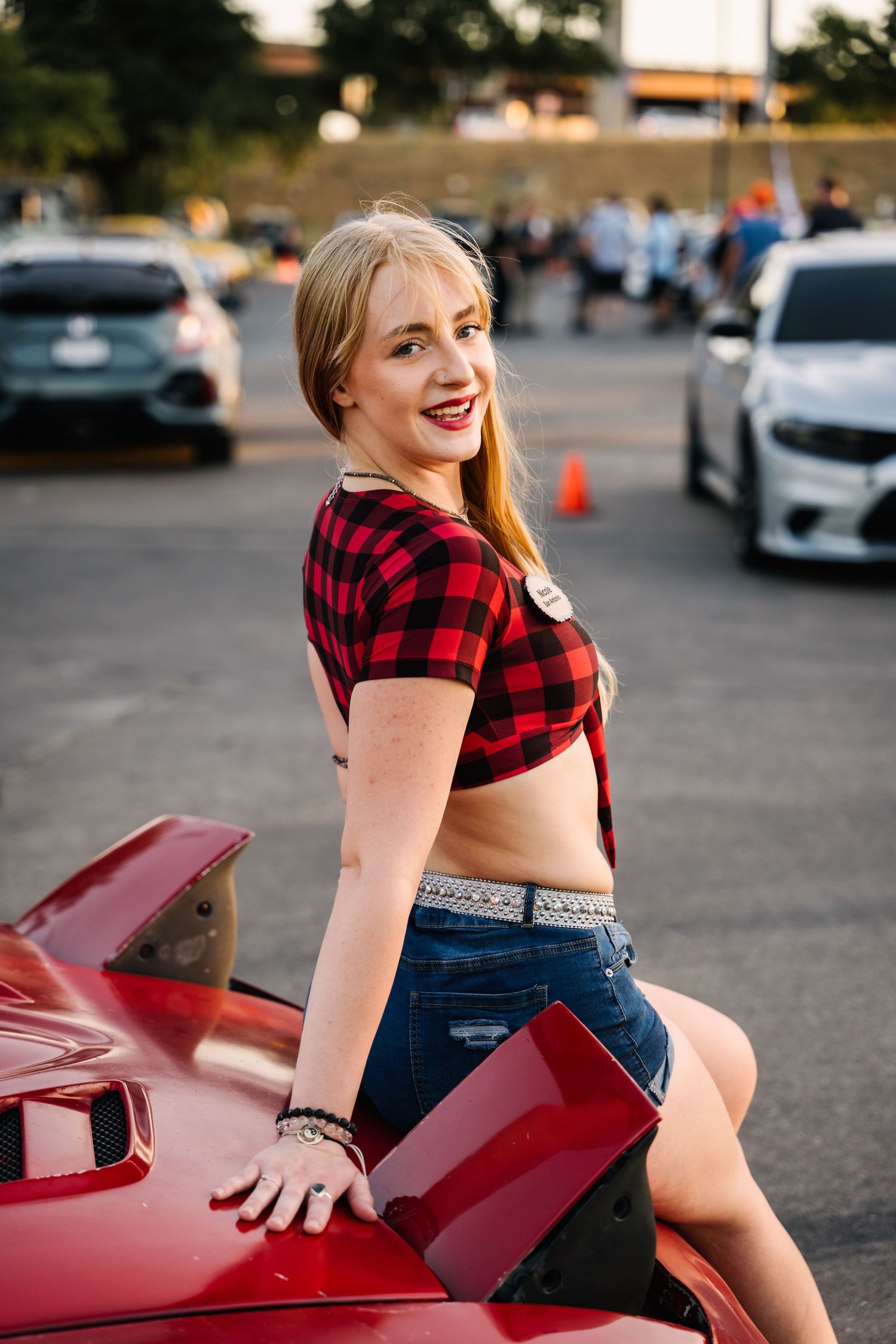 Car enthusiast event with modified vehicles on display at sunset.