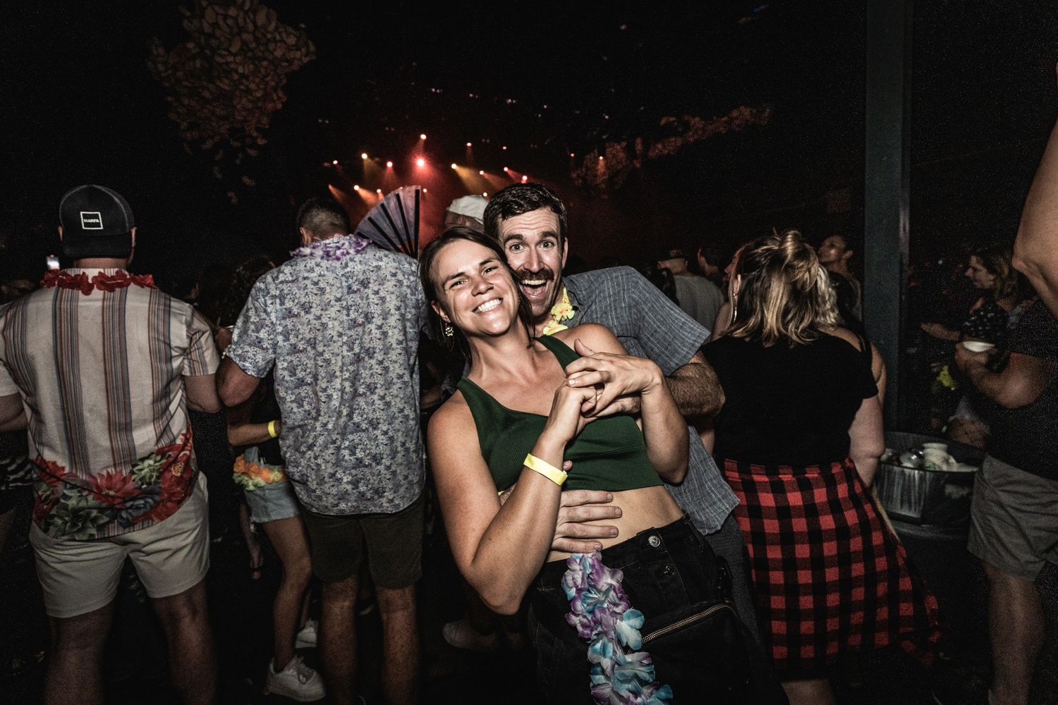 Group of friends embrace while enjoying nighttime outdoor event.