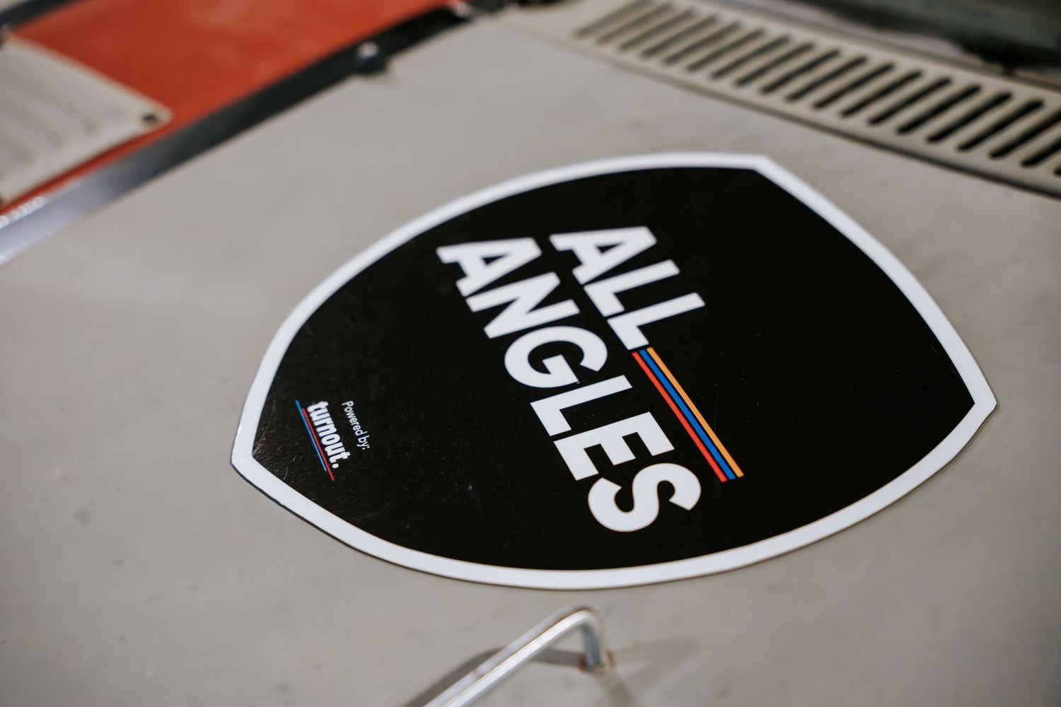 Black and white 'All Angles' automotive sticker decal on a car hood.