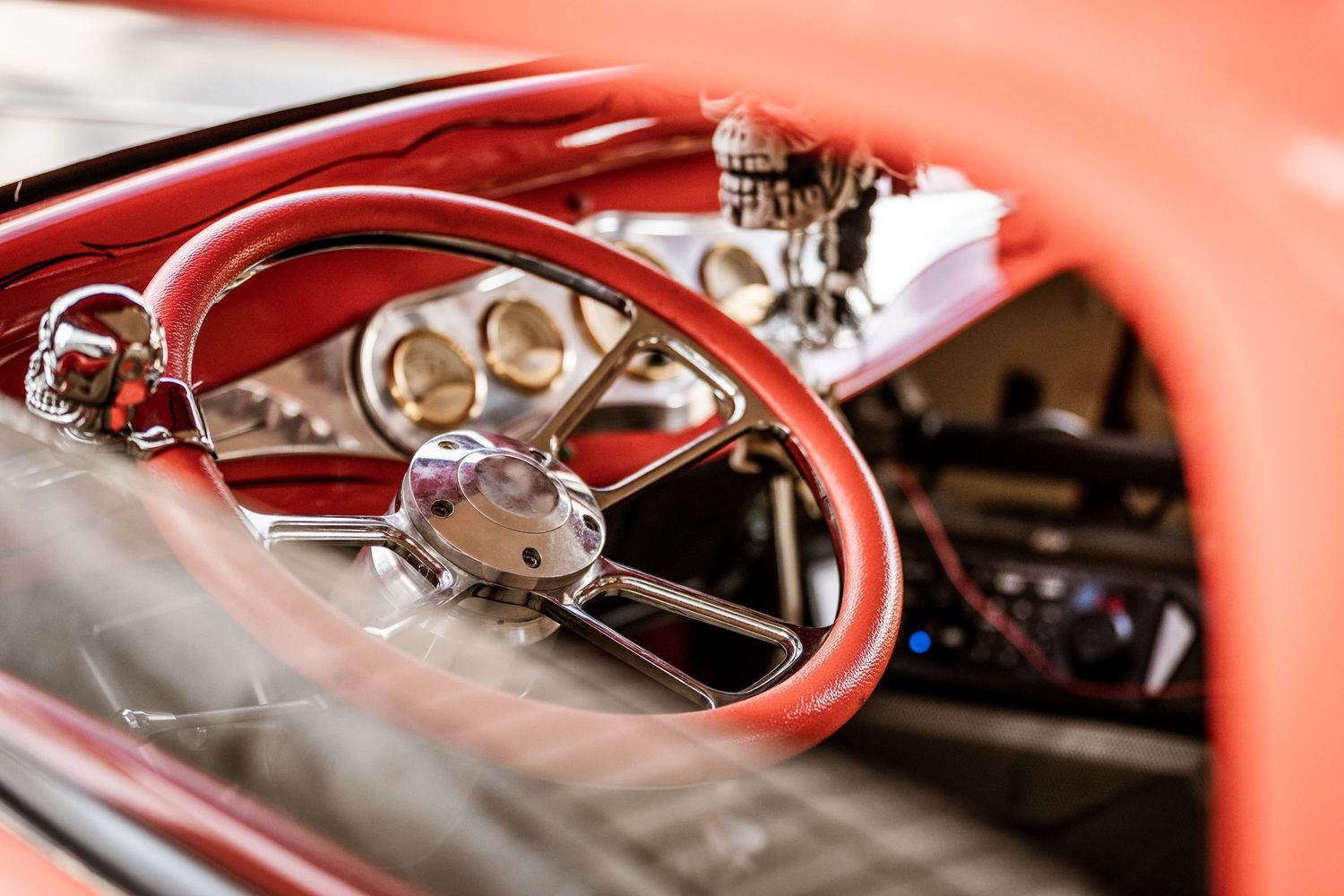 Vintage red steering wheel and dashboard interior of classic car.