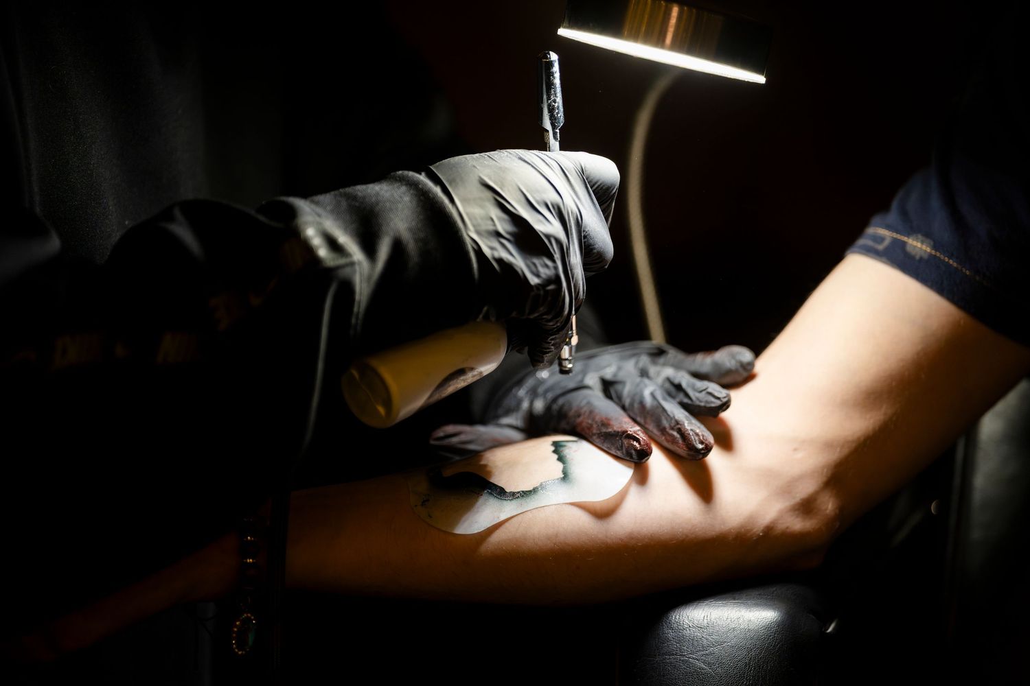 Sequence of hands sewing fabric on a sewing machine in dramatic low lighting conditions.