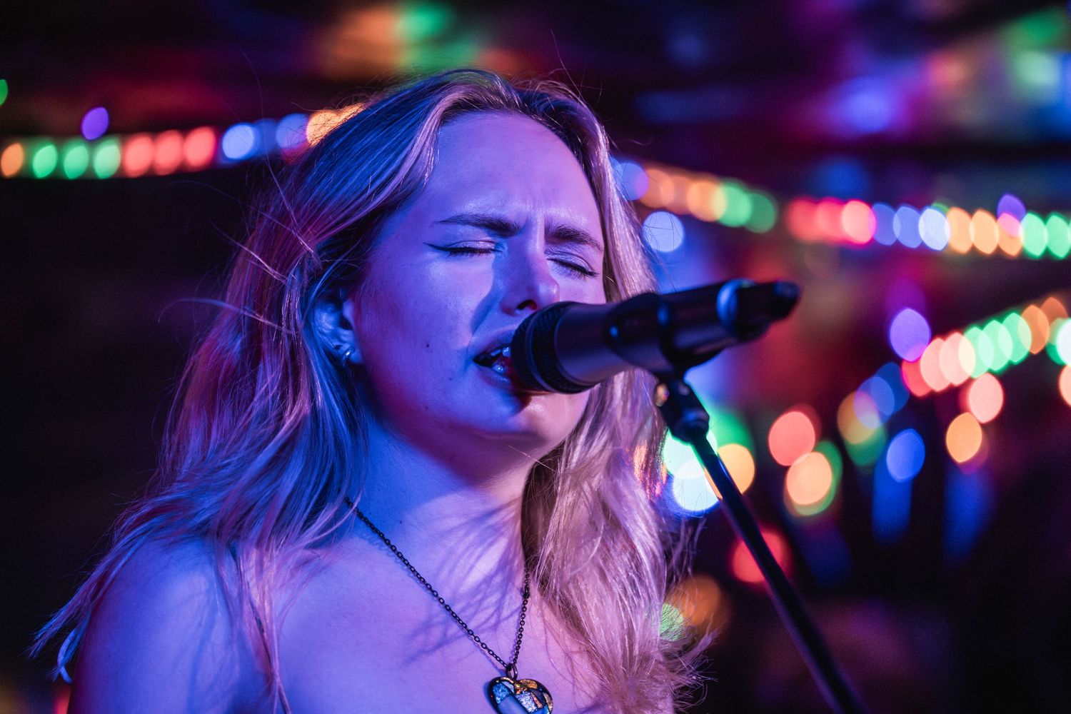 Colorful bokeh lights illuminate a dark nightclub scene with blurred motion and vibrant purple and blue hues.