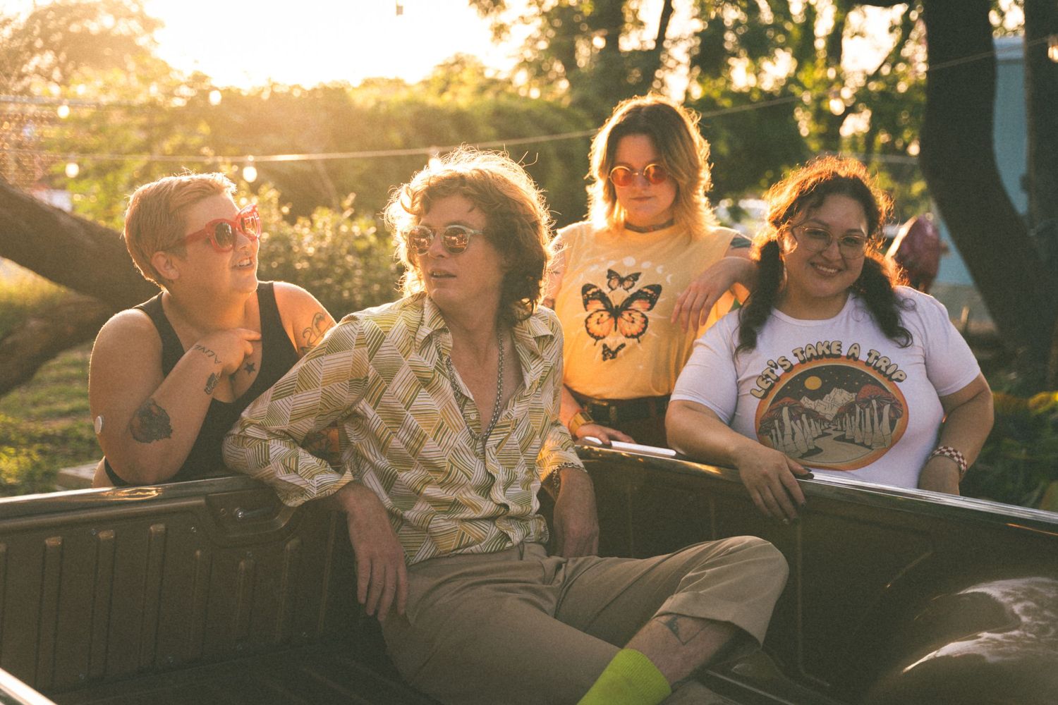 Group of friends laughing together in car during golden hour sunset.