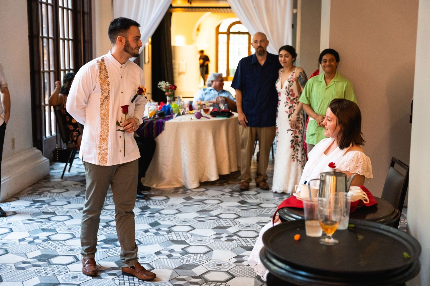 Indoor wedding reception with guests mingling near draped doorway.
