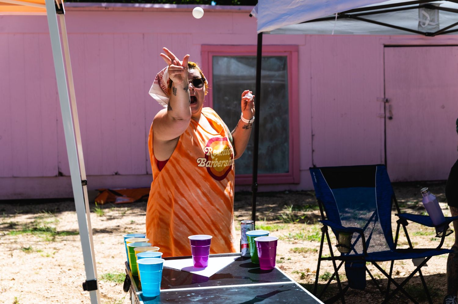 A lively outdoor party scene with drinks and colorful decorations against a pink wall.