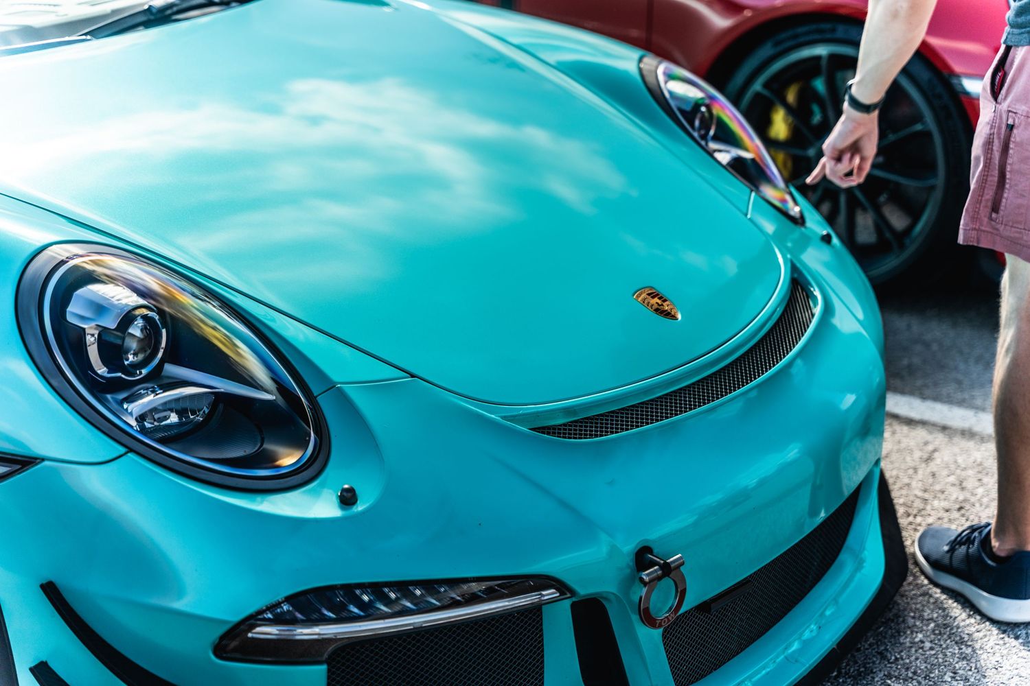 Front view of a turquoise Porsche sports car showing distinctive headlight and hood design.