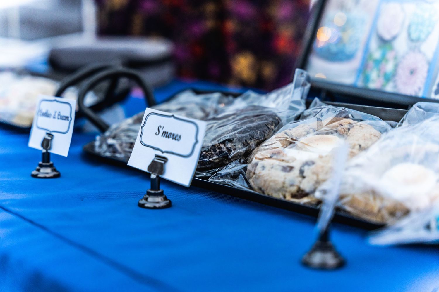 Close-up of labeled food items displayed on a blue table at an outdoor event.