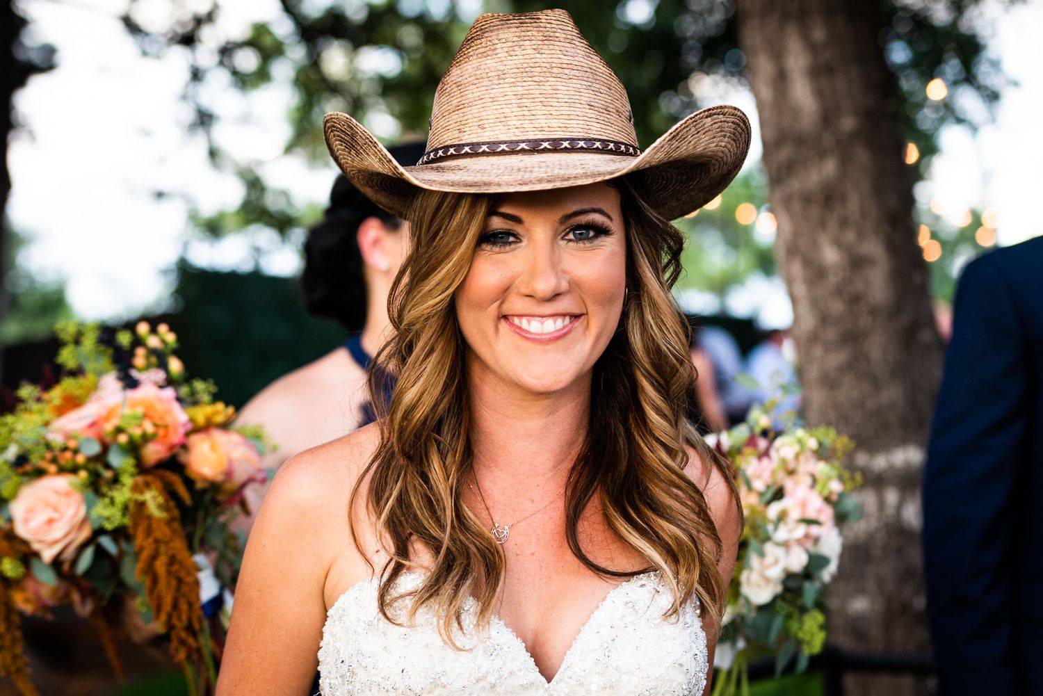 A rustic wedding portrait featuring a cowboy hat and florals in an outdoor setting.