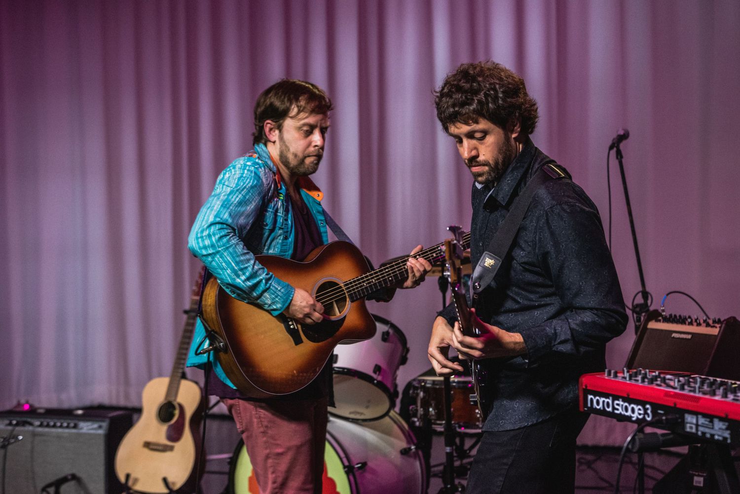 Two guitarists collaborating during performance on stage.