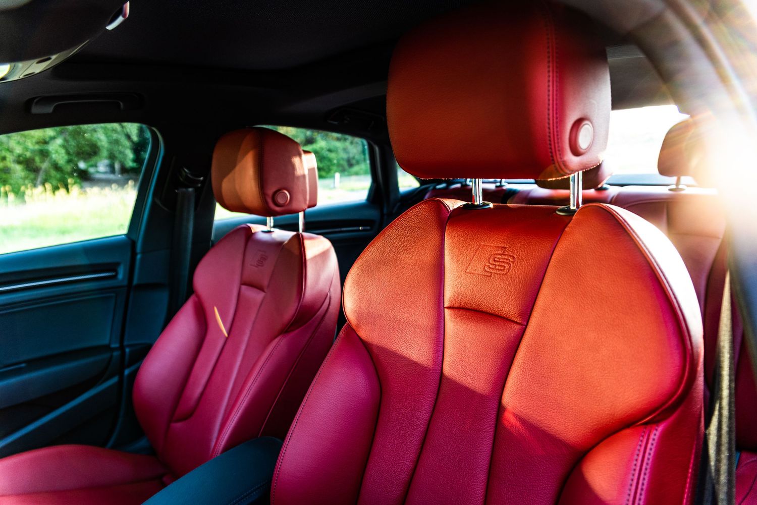 Red leather interior of an Audi showing front and rear sport seats.