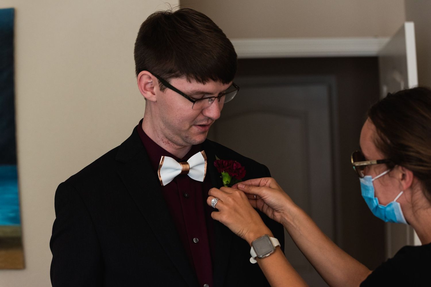 Final wedding day preparations as boutonniere is pinned to formal attire.