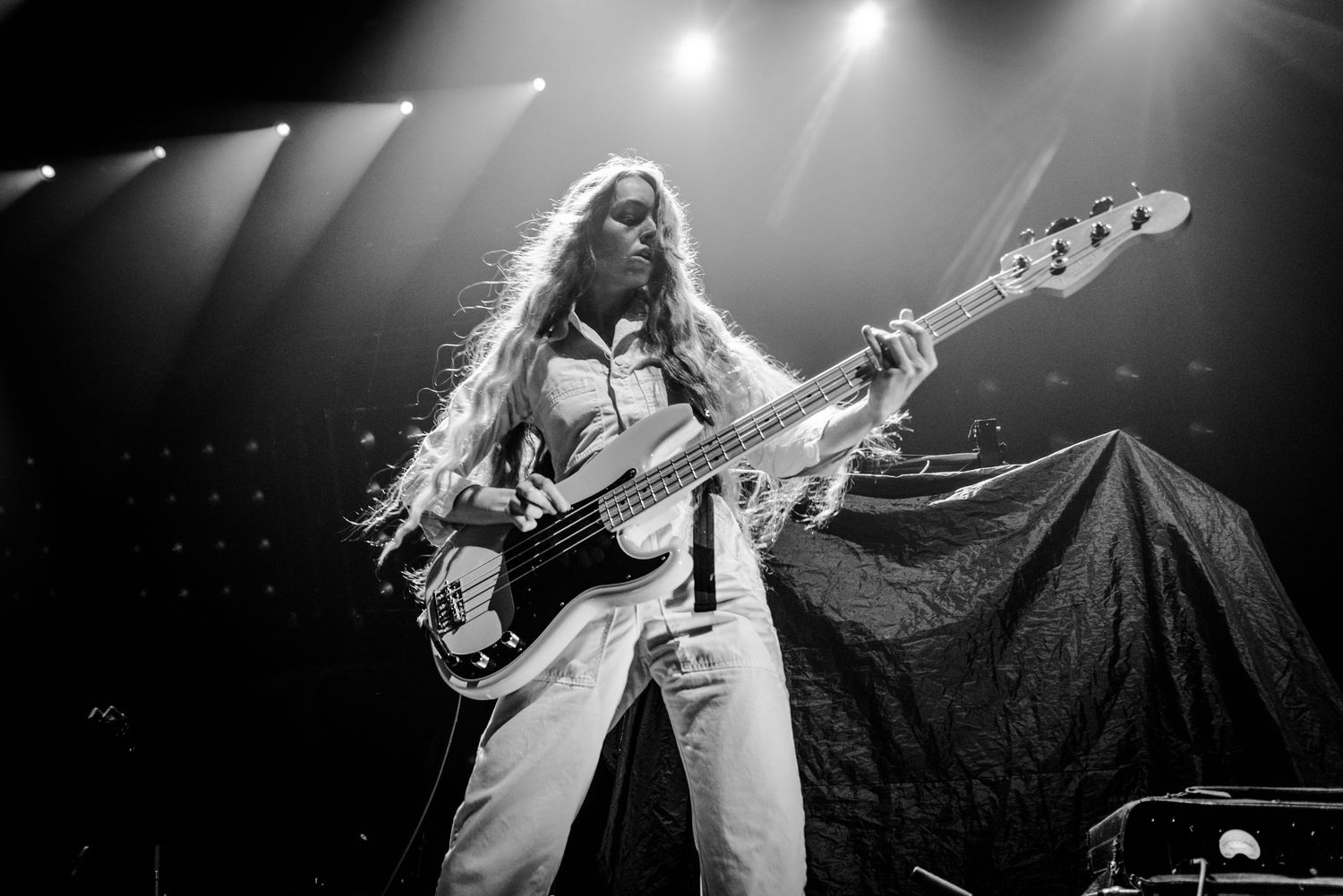 Concert photographer captures musician playing bass guitar in dramatic stage lighting.