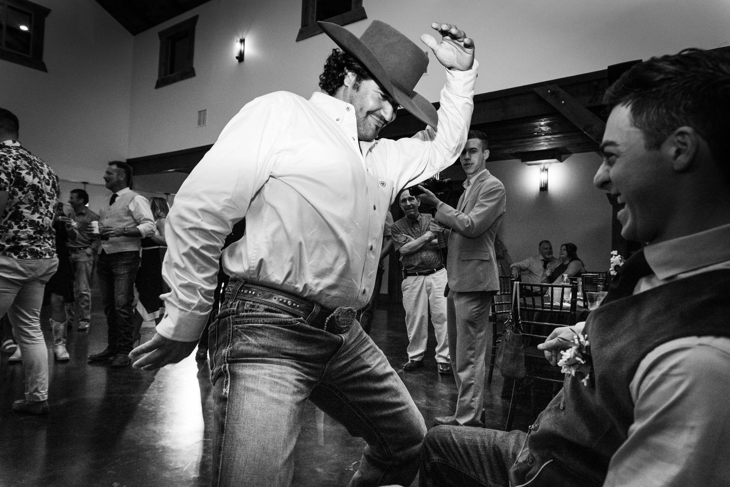 Guest dances enthusiastically in black and white at wedding reception.