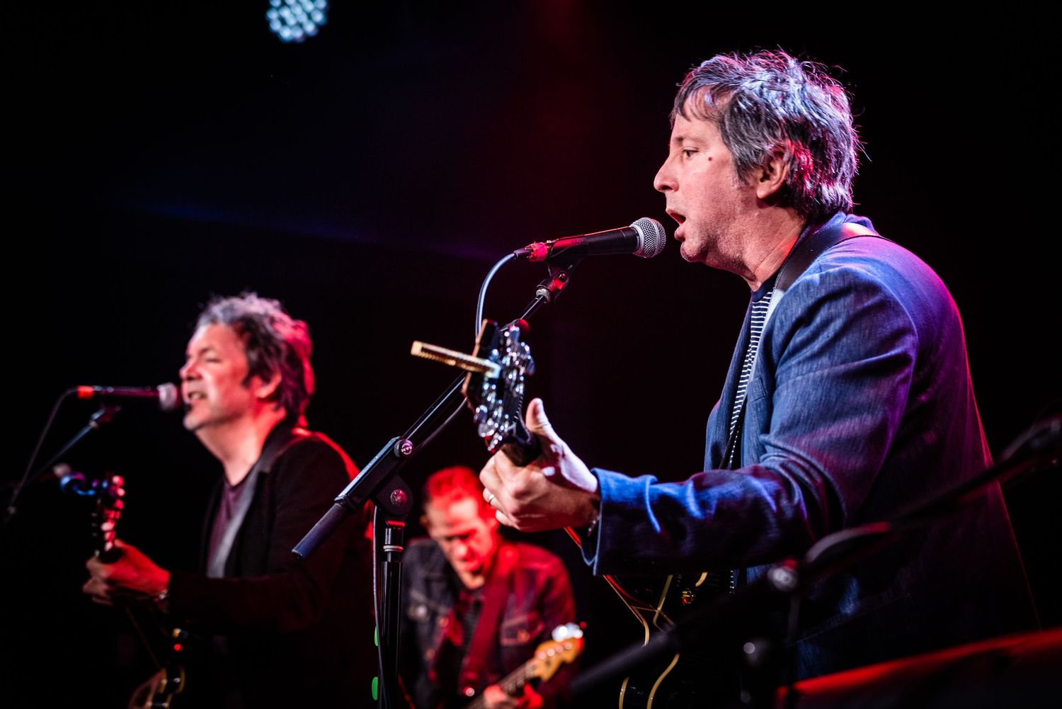 Musicians perform together under blue stage lights during live concert.