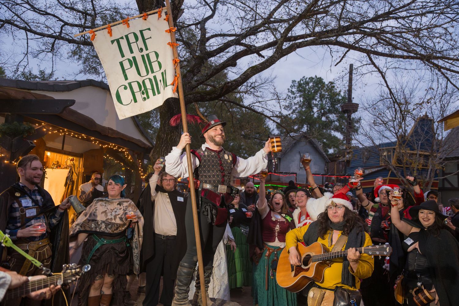A crowd gathers around performers with signs and musical instruments at an outdoor festival.