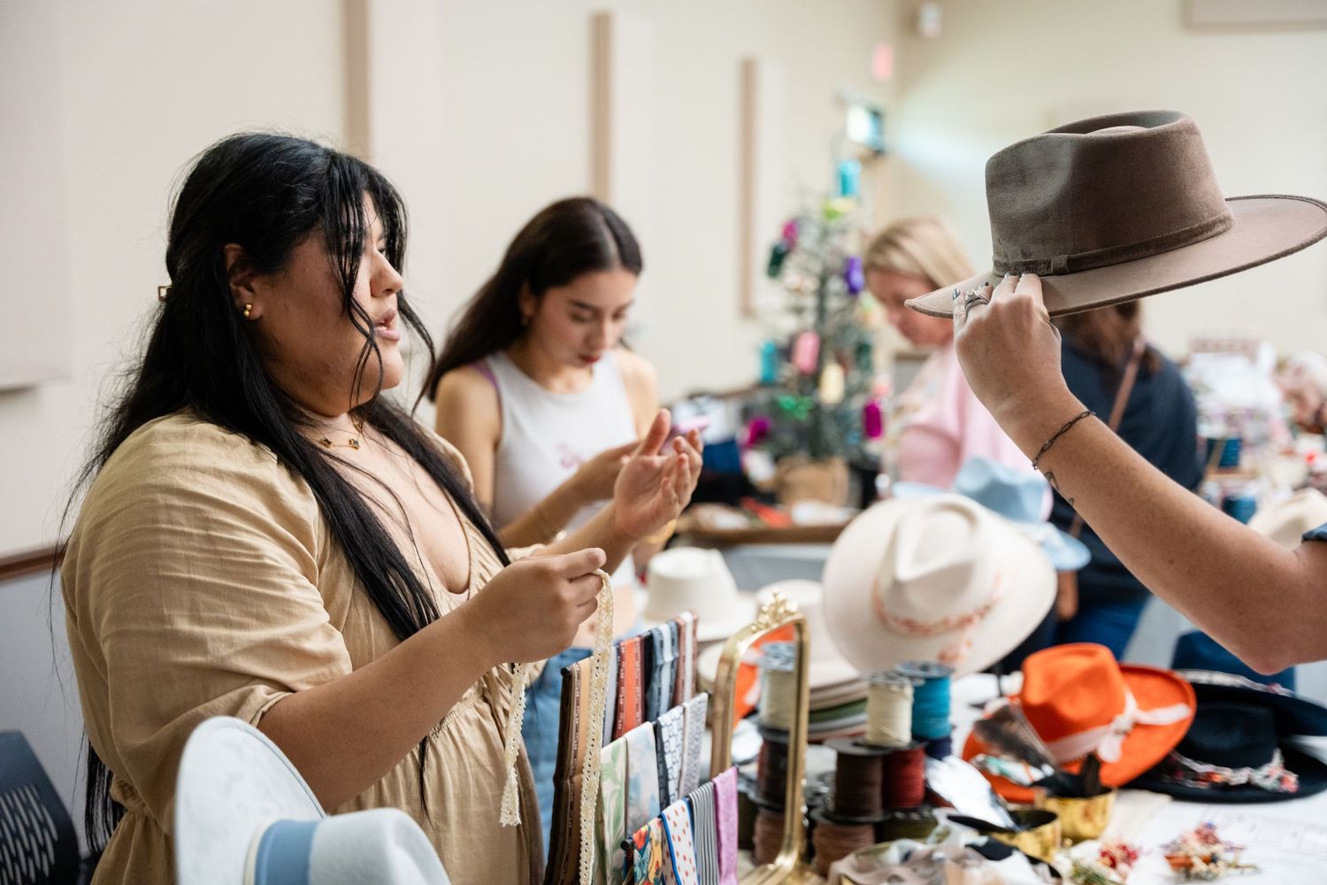 People examining and discussing items at a craft market or vendor booth.