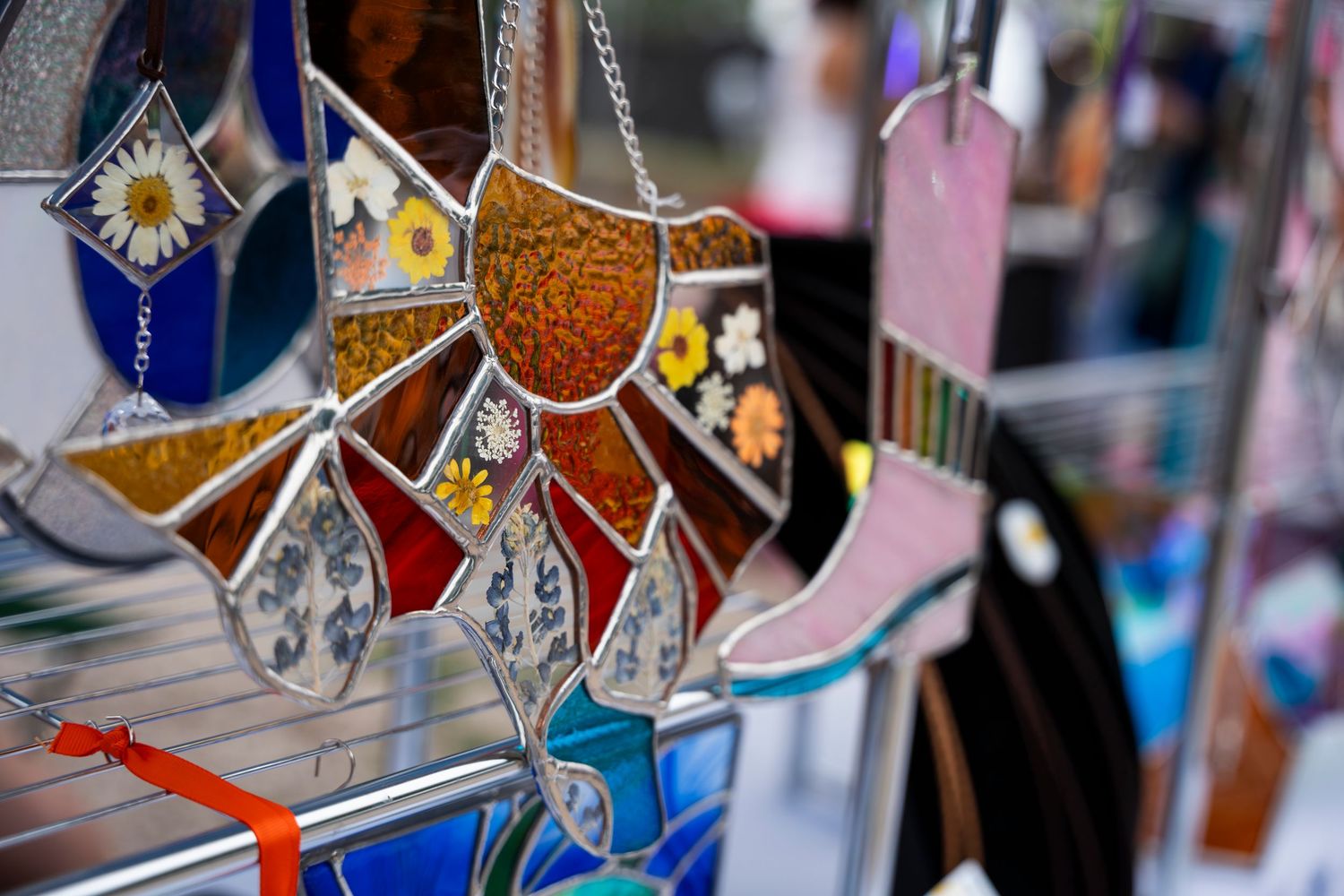 Colorful glass artwork on display features delicate geometric shapes and crystal-like patterns backlit against a window.