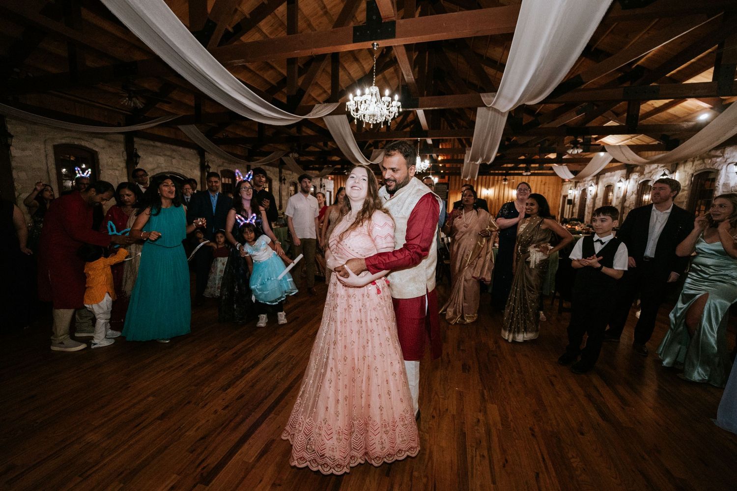 Couple sharing a romantic slow dance at an indoor reception with elegant decor and lighting.