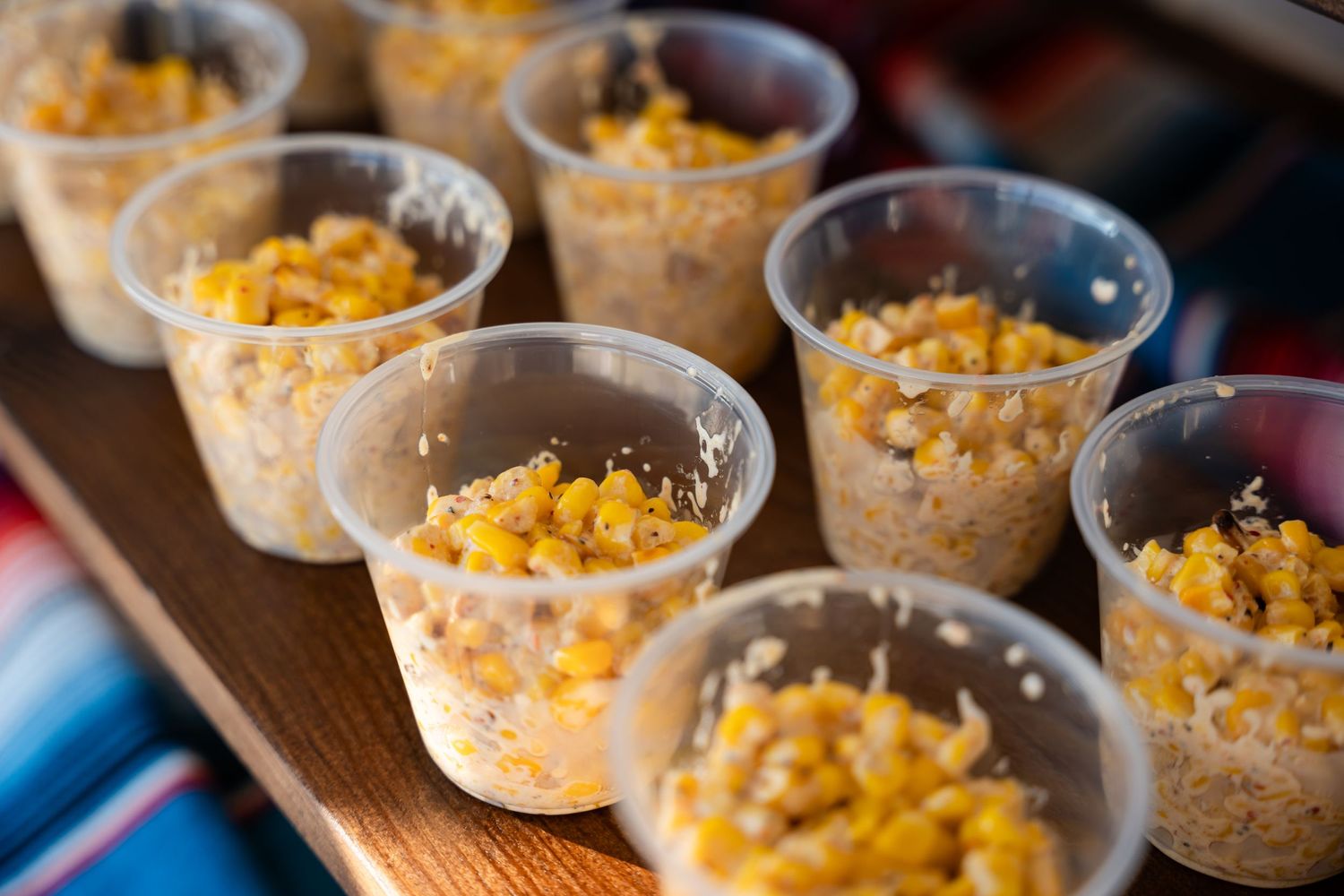Individual servings of creamy dessert topped with shredded cheddar cheese arranged on a wooden board.
