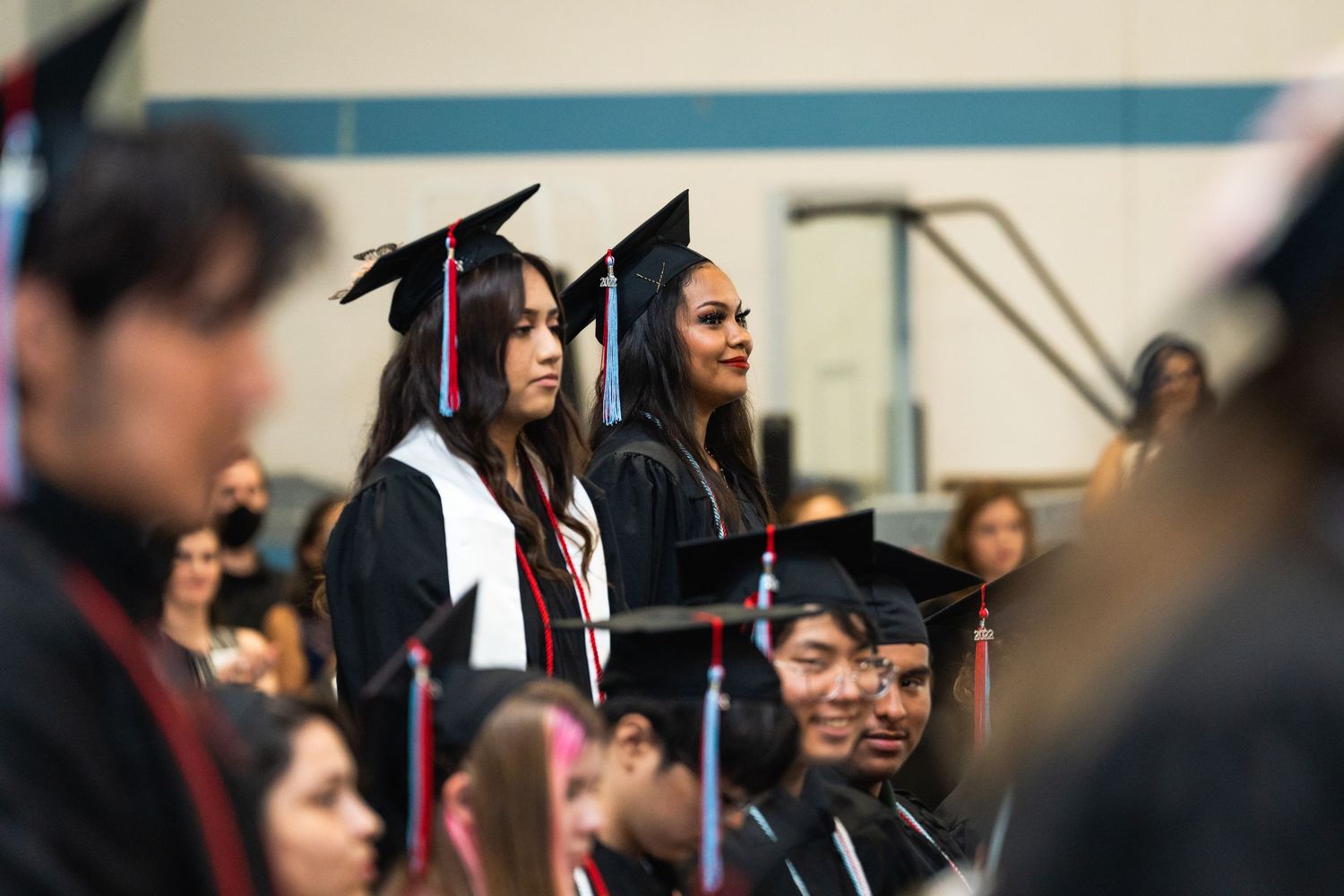 Graduates in caps and gowns stand during commencement ceremony.